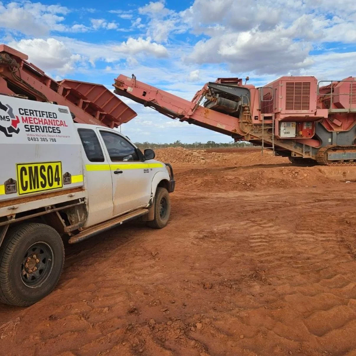 A construction site scene with a large pink rock crusher and a white service truck with repeated text reading 'Certified Mechanical Services.' The sky is partly cloudy and the ground is reddish dirt.