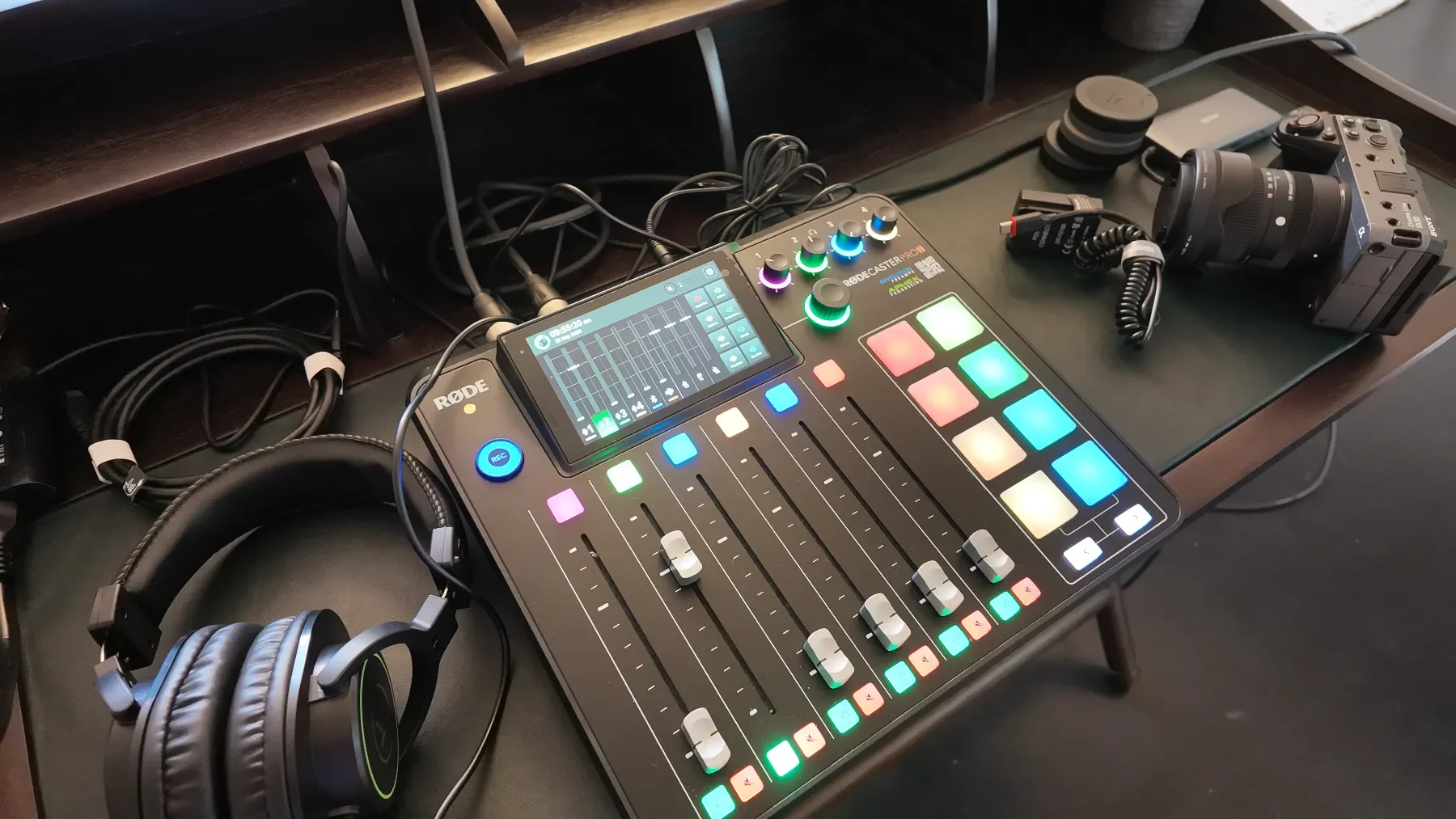 Audio technician setup on a black table with a sound mixer, headphones, camera, and audio equipment, with multicolored illuminated buttons and sliders at Studio Analogue, Singapore Boutique Podcast and vodcast recording studio