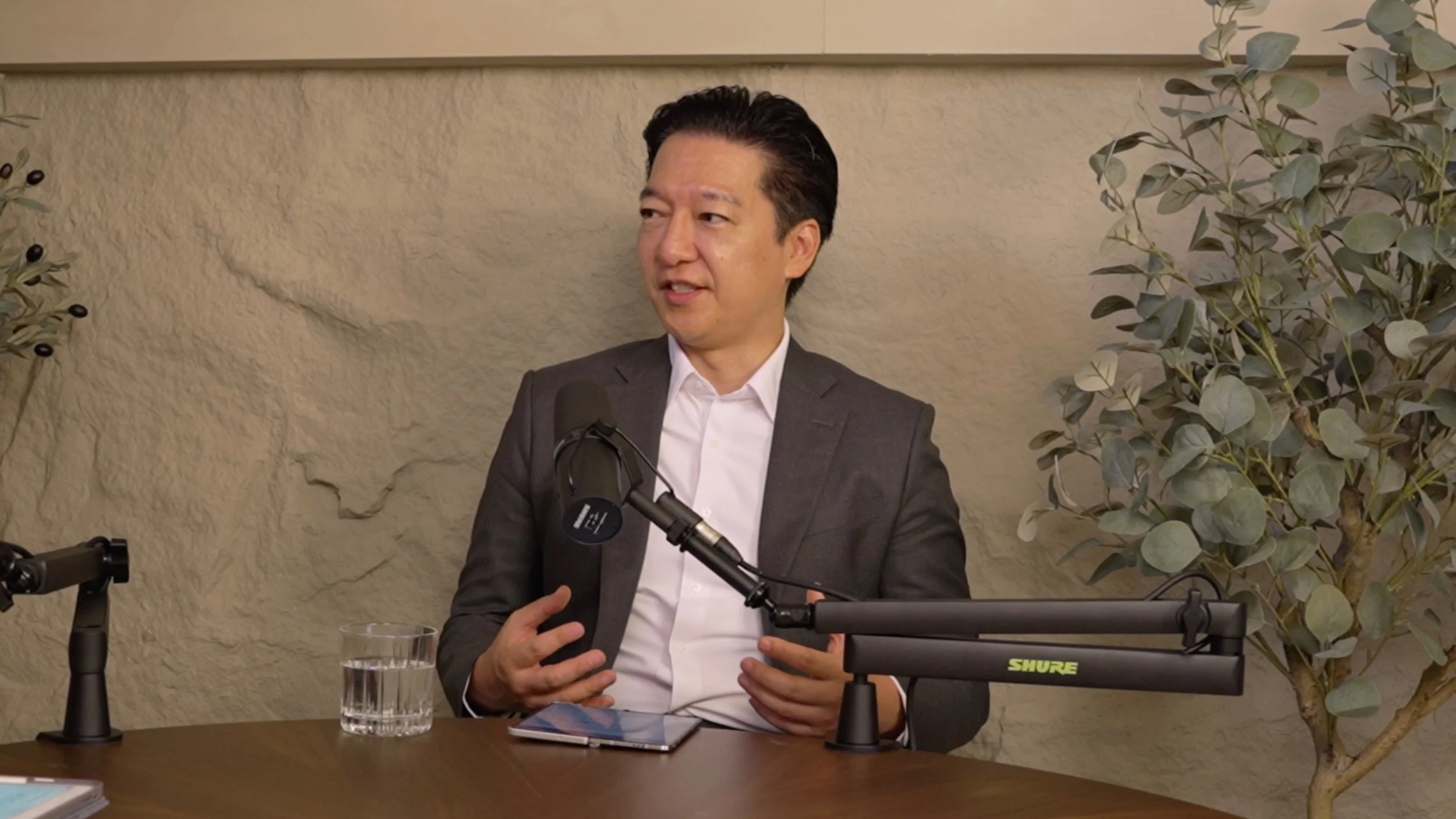 A man in a suit and white shirt speaking into a microphone during a podcast interview at Studio Analogue - boutique podcast recording studio at Kampung Bahru.