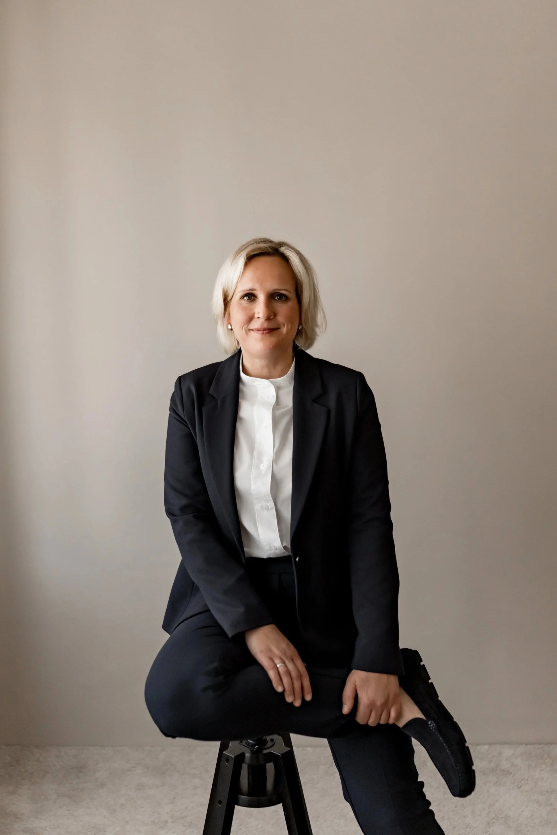 Monique Fordt, Coach und Beraterin, sitzt auf einem Hocker und blickt direkt in die Kamera