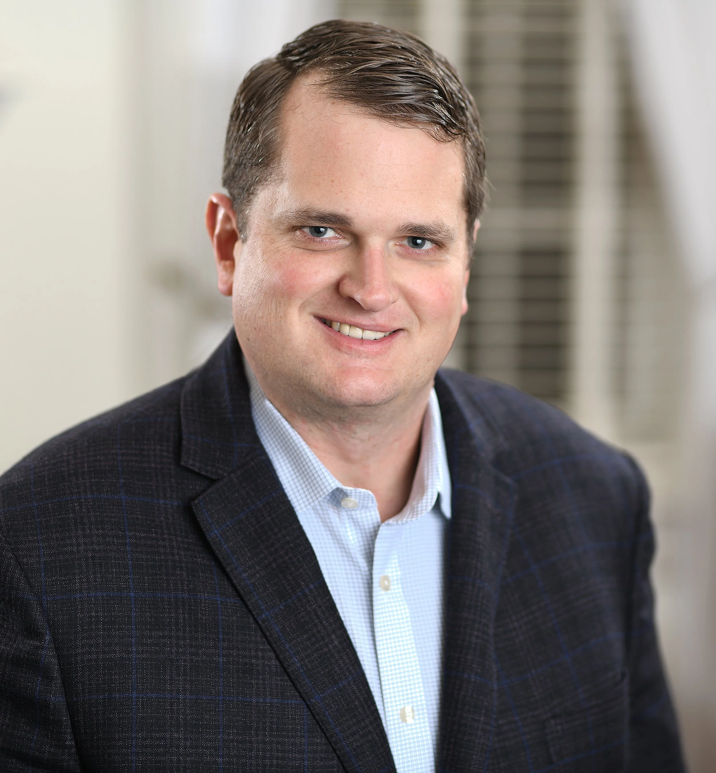 Headshot of Ben Seals, Founder & Managing Partner, smiling in a pine striped blazer