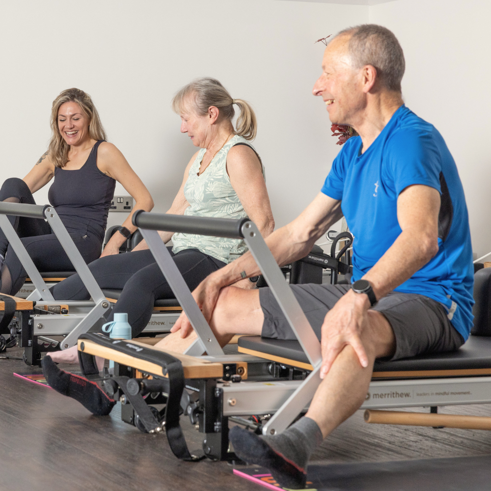 People participating in a Reformer Pilates workout class using specialized Reformer machines.