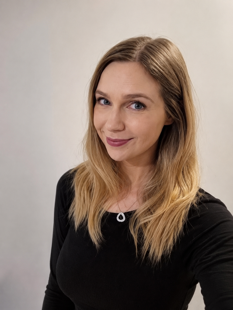 Instructor, Rachel Chapman, with long blonde hair and blue eyes smiling at the camera, wearing a black top against a white background.