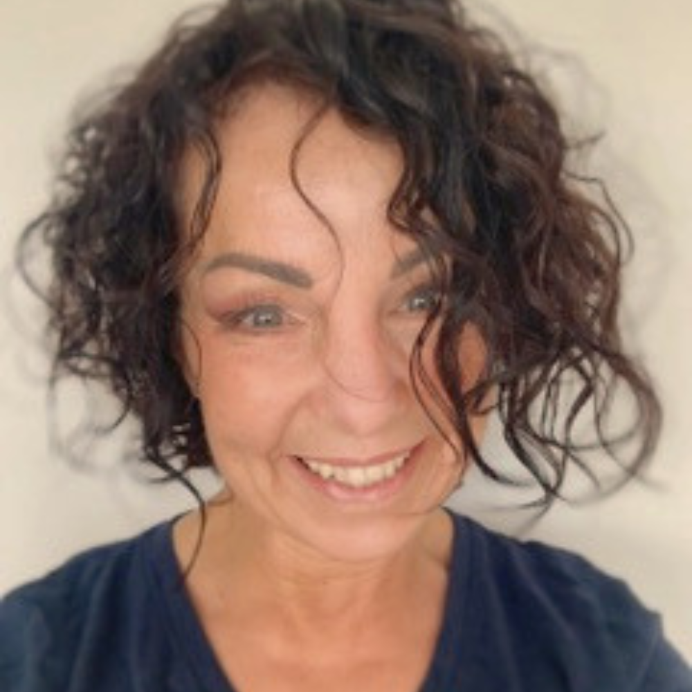 Instructor, Anna Baker, with dark curly hair smiling, wearing a dark top.