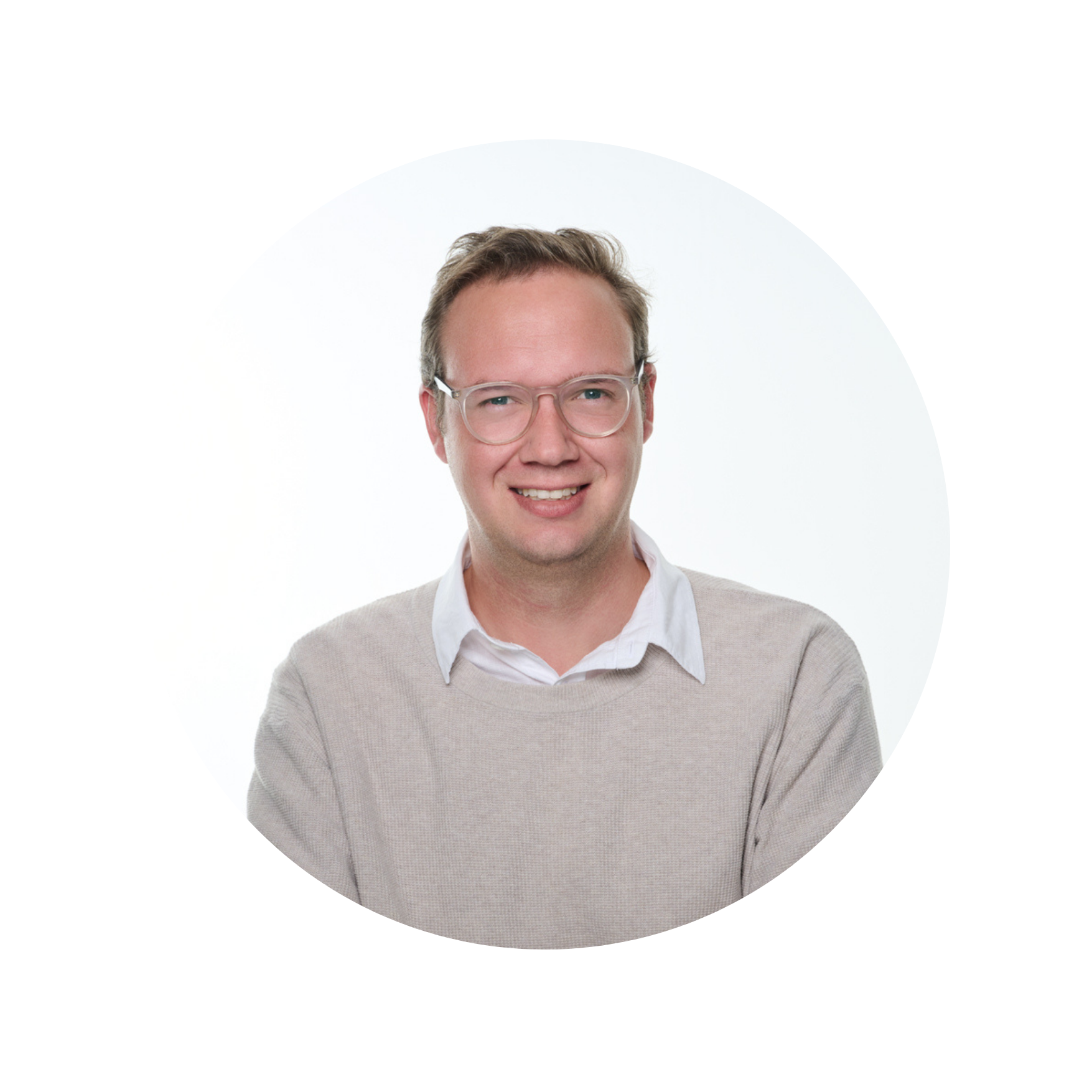 A man with light brown hair and glasses, wearing a beige sweater over a collared shirt, smiling against a white background with black and colorful distortion effects.