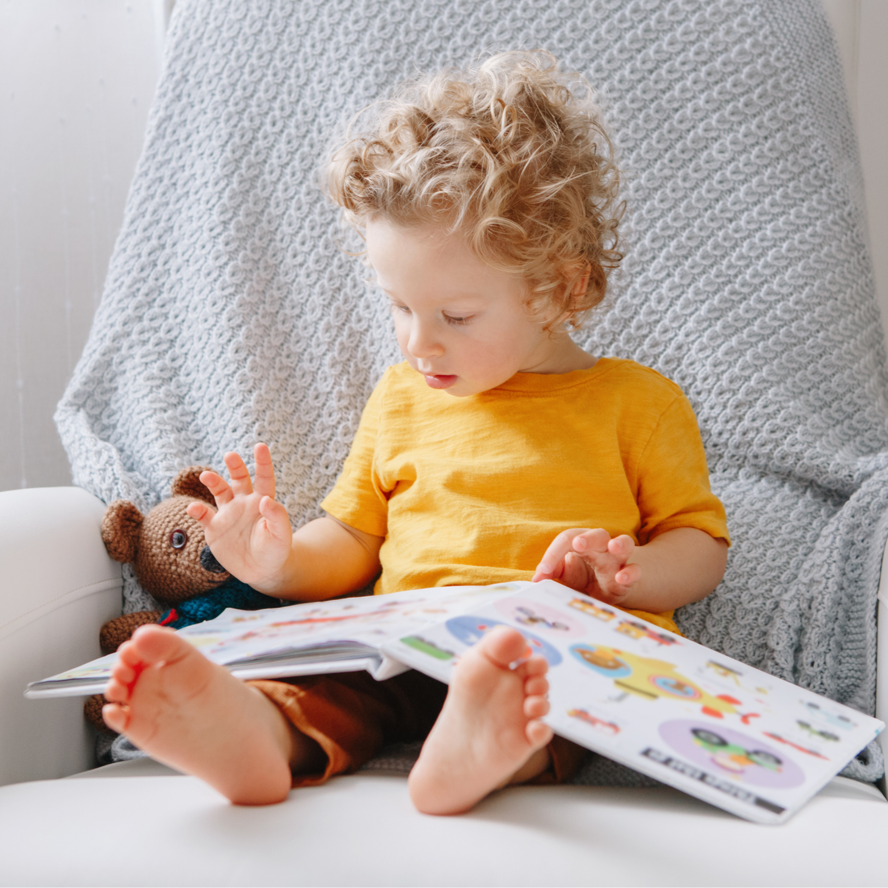 Young child reading with a soft toy, Moya's in-home babysitting service for guests in Cape Town.