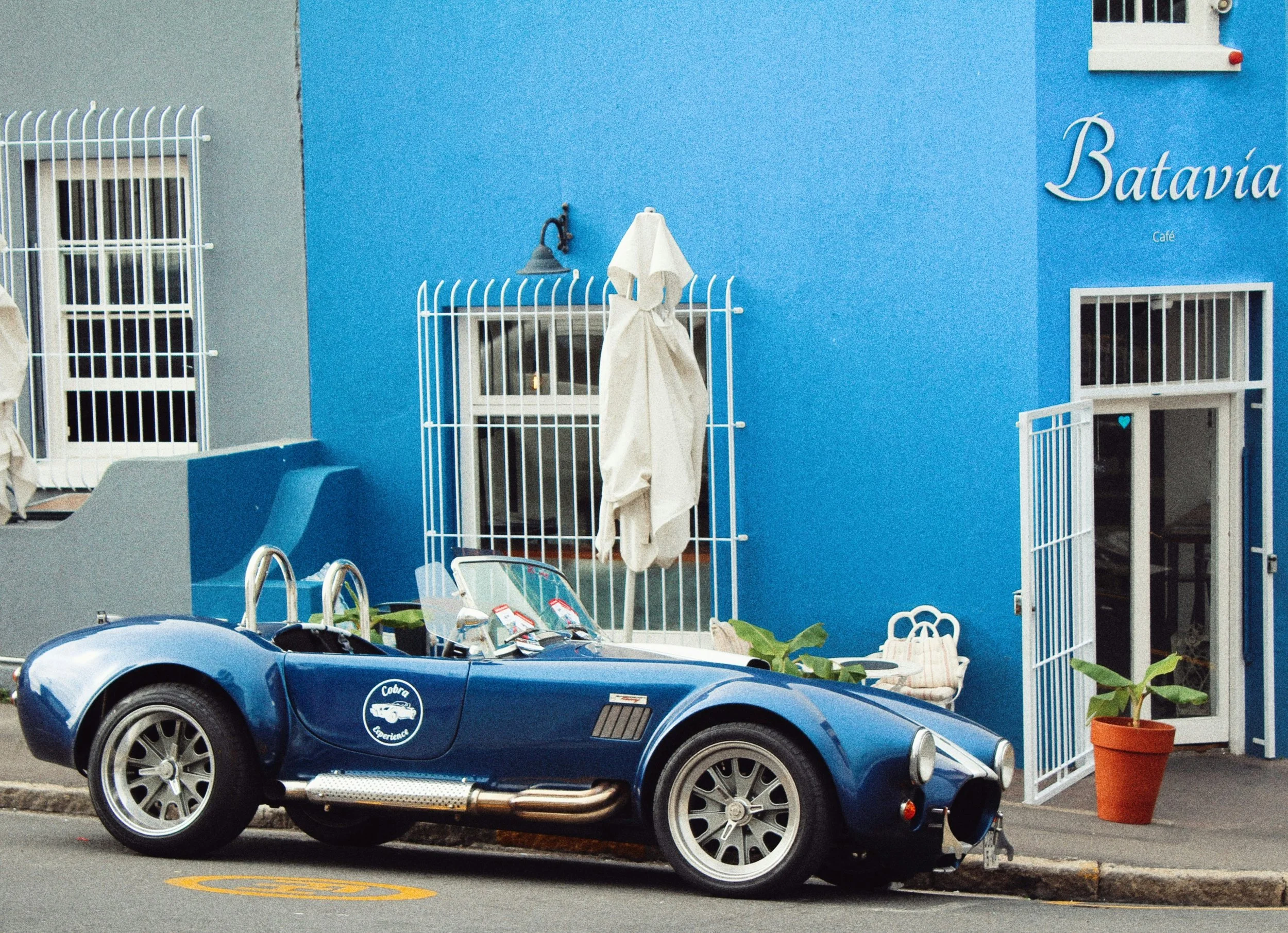 Vintage blue Cobra sports car parked on a colourful Bo-Kaap street in Cape Town during the Cobra driving experience.