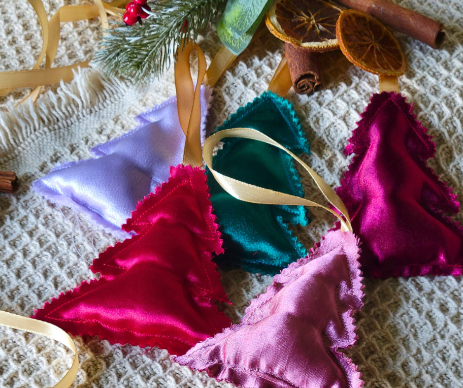Colorful satin fabric Christmas bunting decorations with ribbons on beige textured surface.