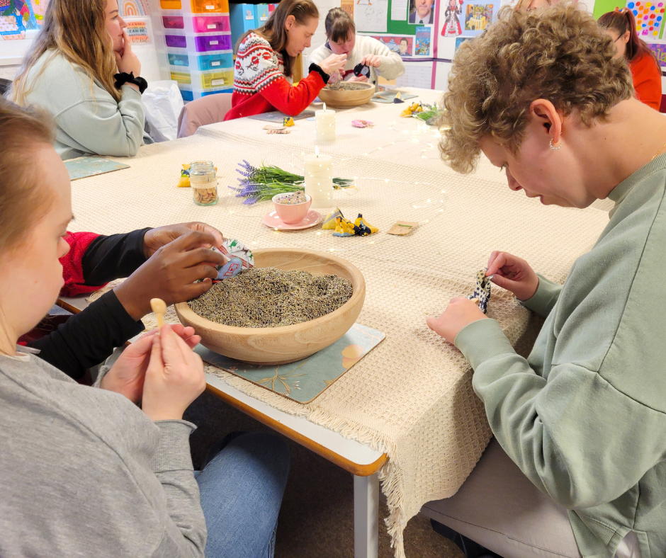 Adults with disabilities sitting around a large table engaged in a lavender workshop activity.