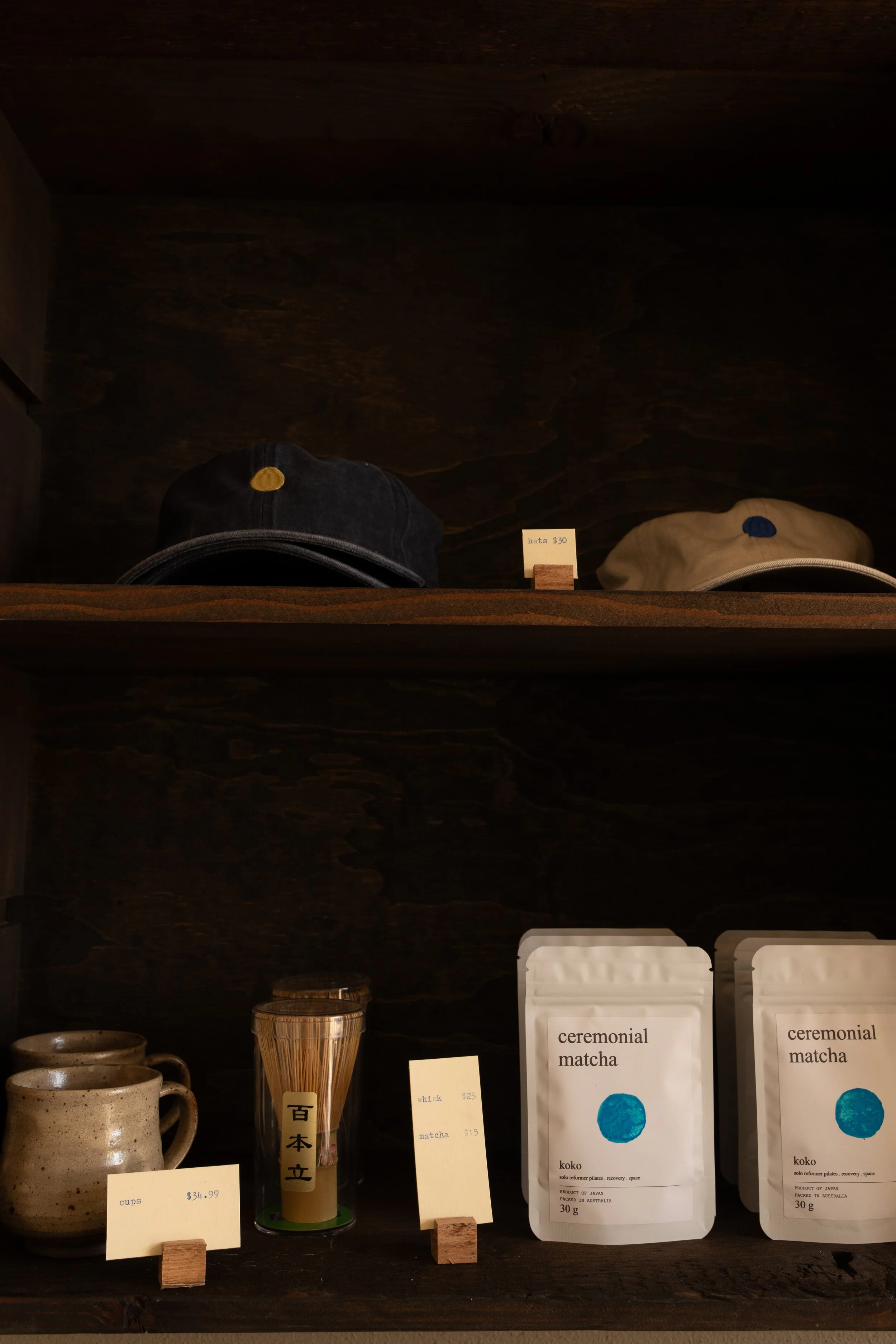 A wooden shelf displaying retail items from koko studio, Japanese inspired wellness studio with reformer pilates, strength, sauna and ice bath located at Erina, Central Coast.