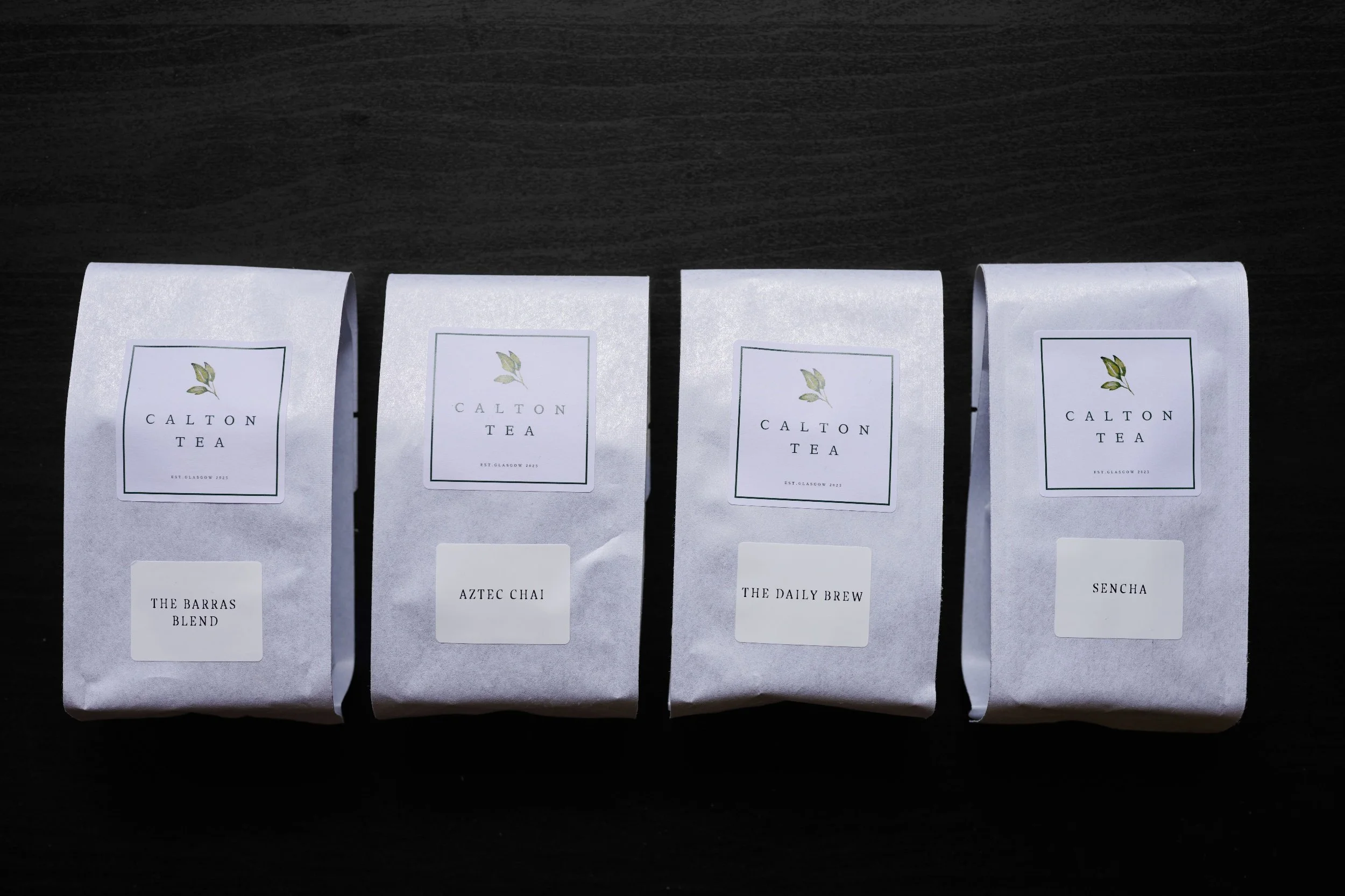 4 white branded bags of tea lined out on a black background