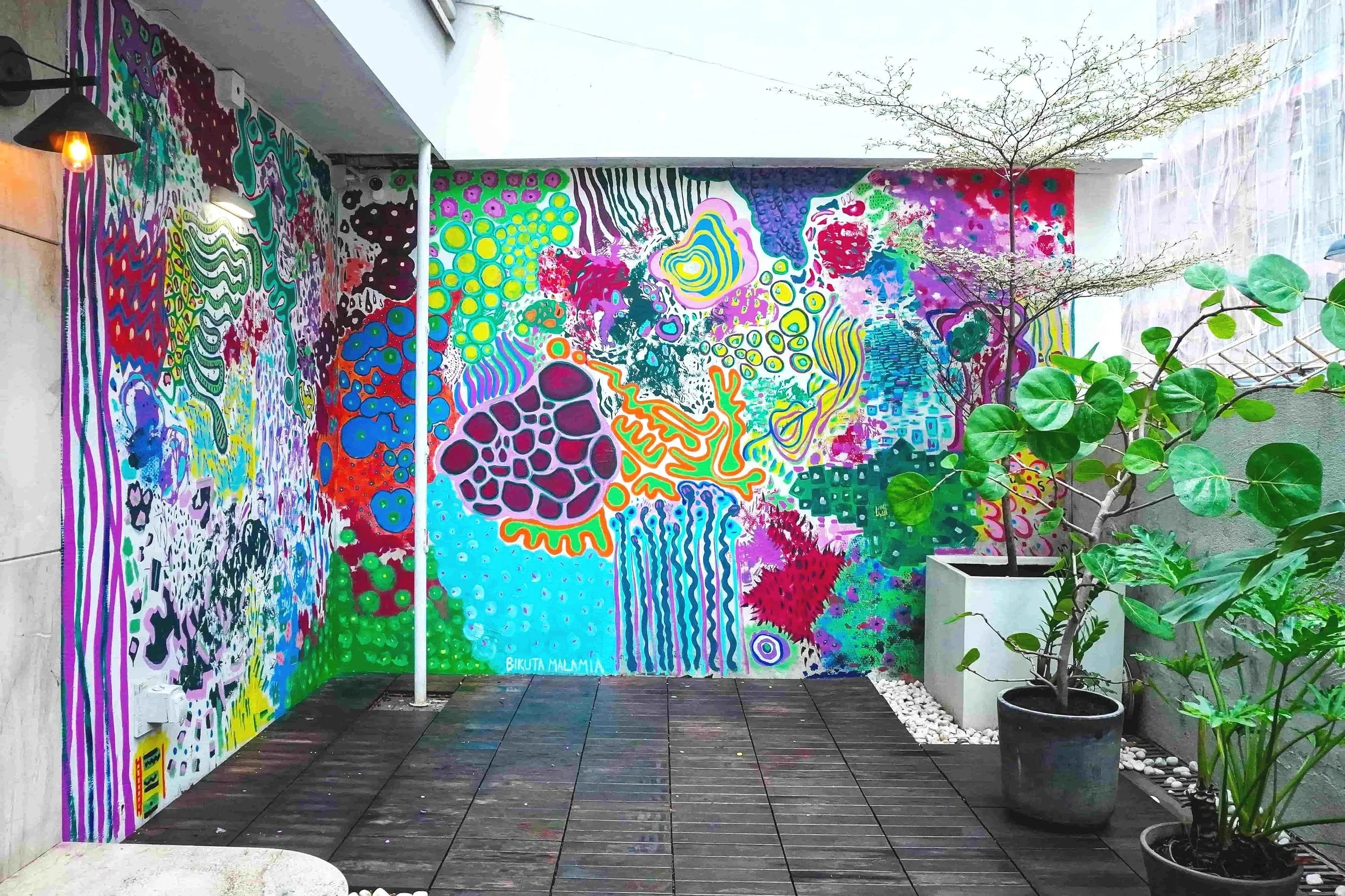 A artistic & dynamic mural filled with vibrant colors and intricate designs, enhancing the space around a potted plant.