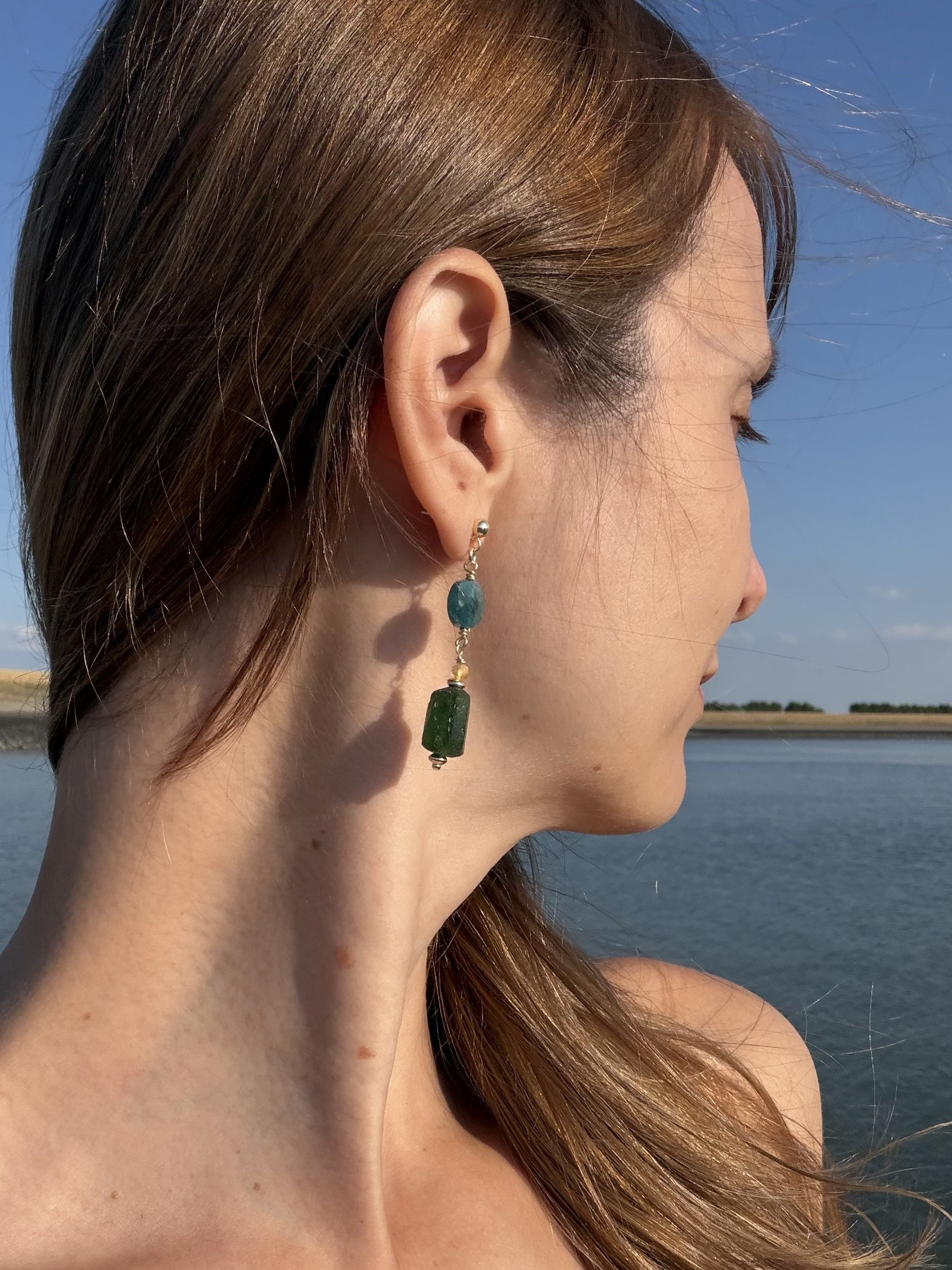 Handmade green gemstone drop earring worn by the sea.