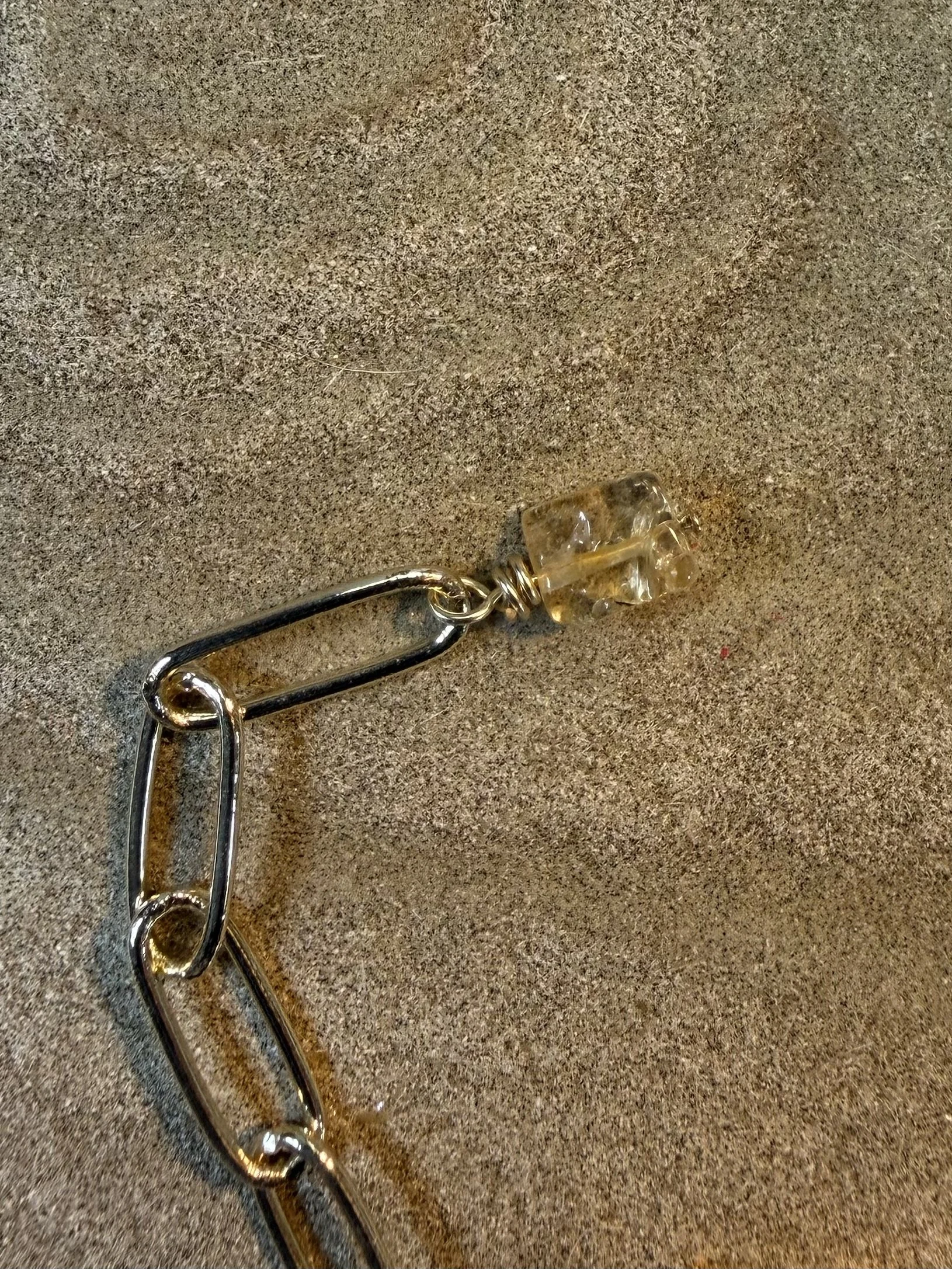 Close-up of the necklace chain finished with a small translucent golden gemstone bead.