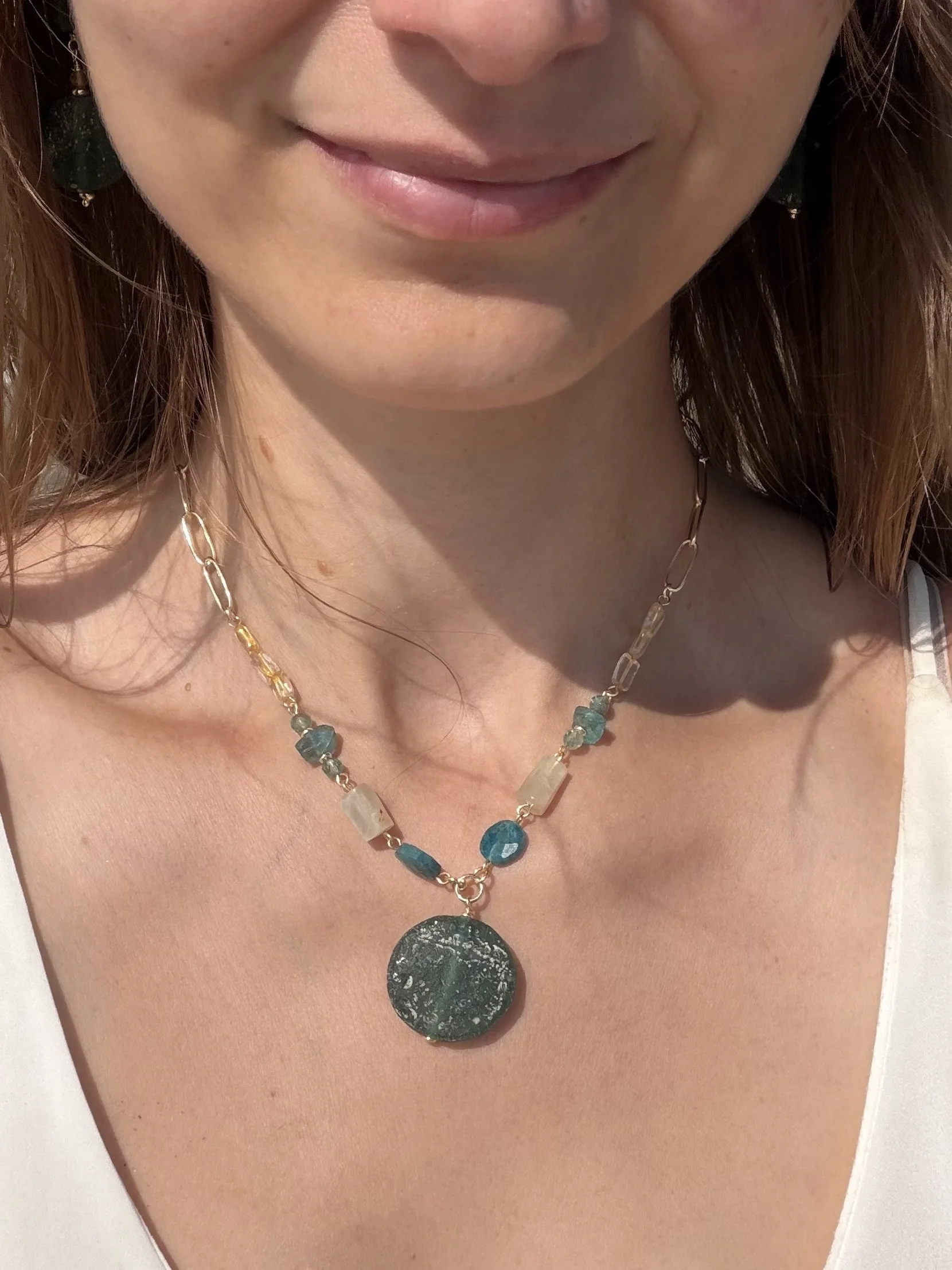 Handmade gemstone pendant necklace with green and turquoise stones worn at the collarbone, showing the length of the pendant.