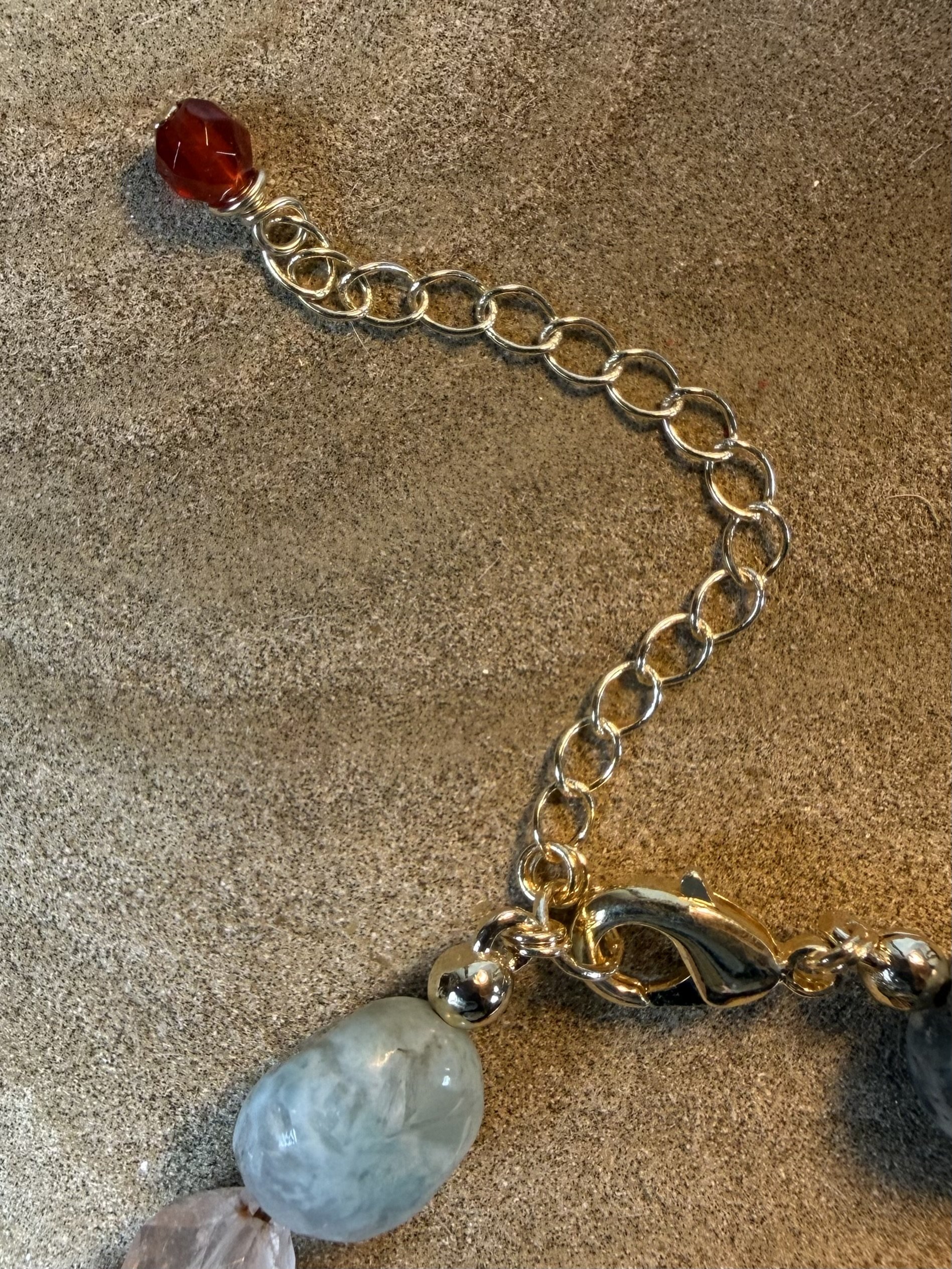 Close-up of the gold clasp and adjustable chain of a handmade gemstone bracelet.