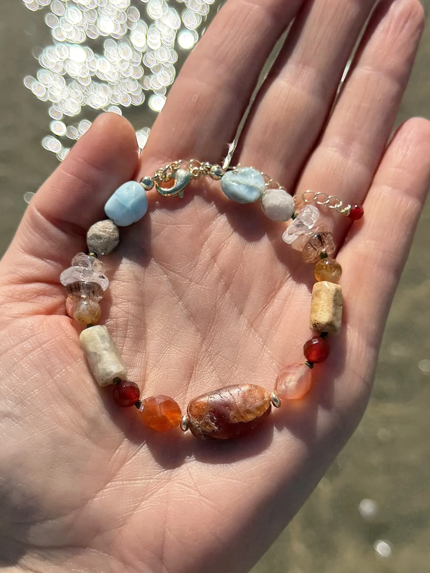 Colourful handmade gemstone bracelet held in a hand, showing the mix of natural stones, shapes and textures.