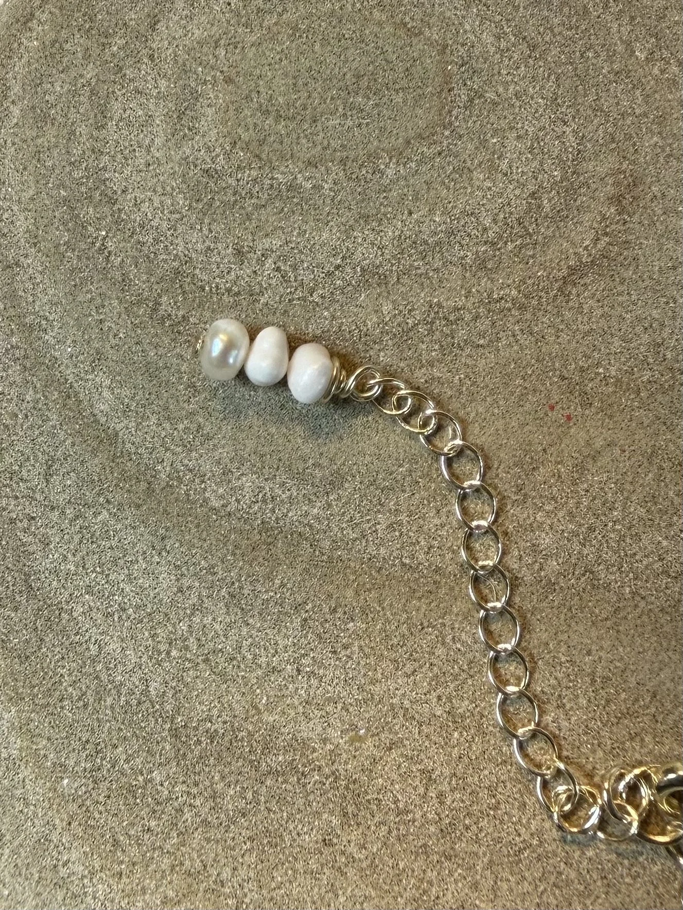 Close-up of the adjustable necklace chain finished with small white beads.
