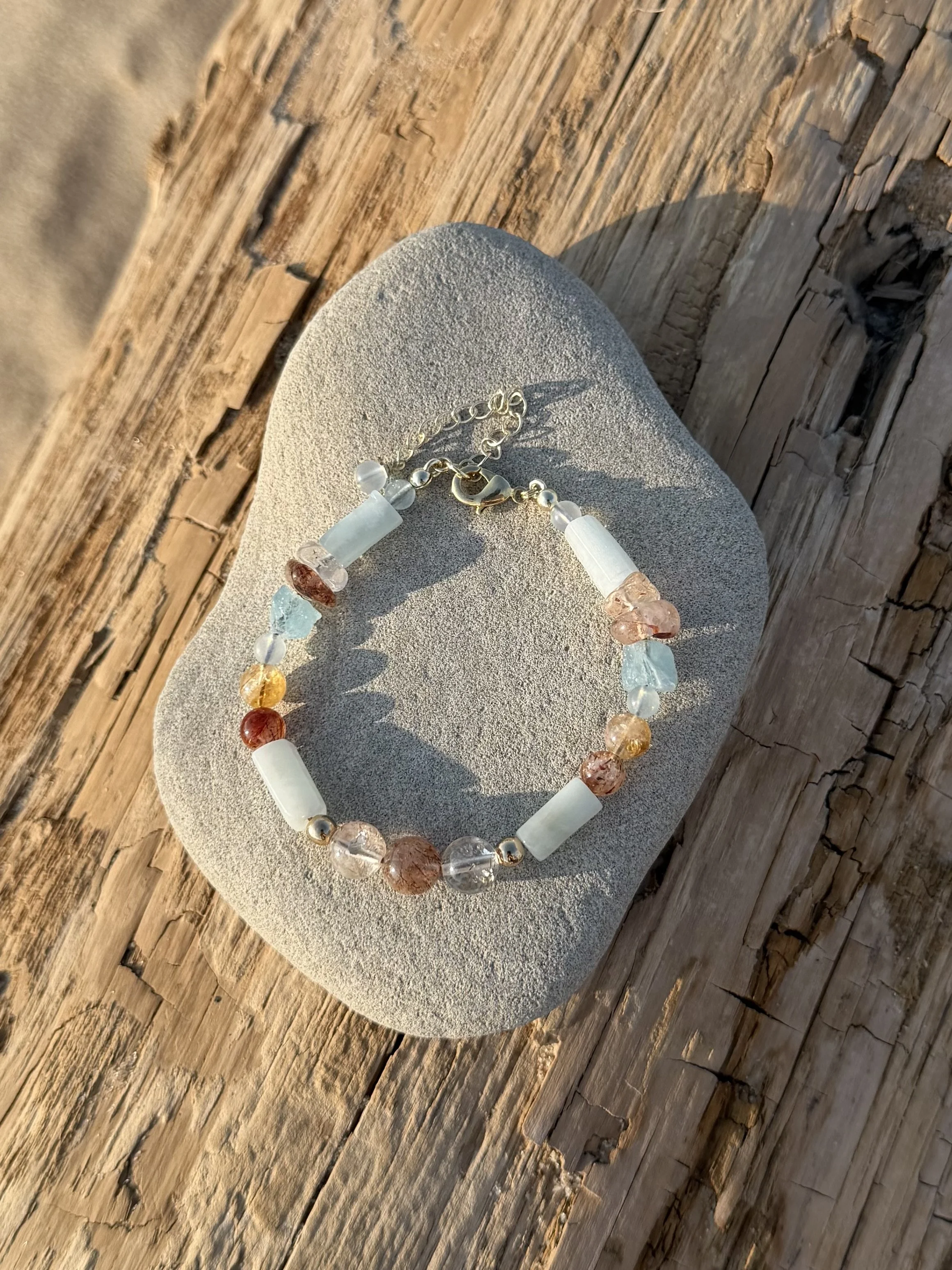 Colorful beaded necklace resting on a smooth, oval-shaped stone on a wooden surface.