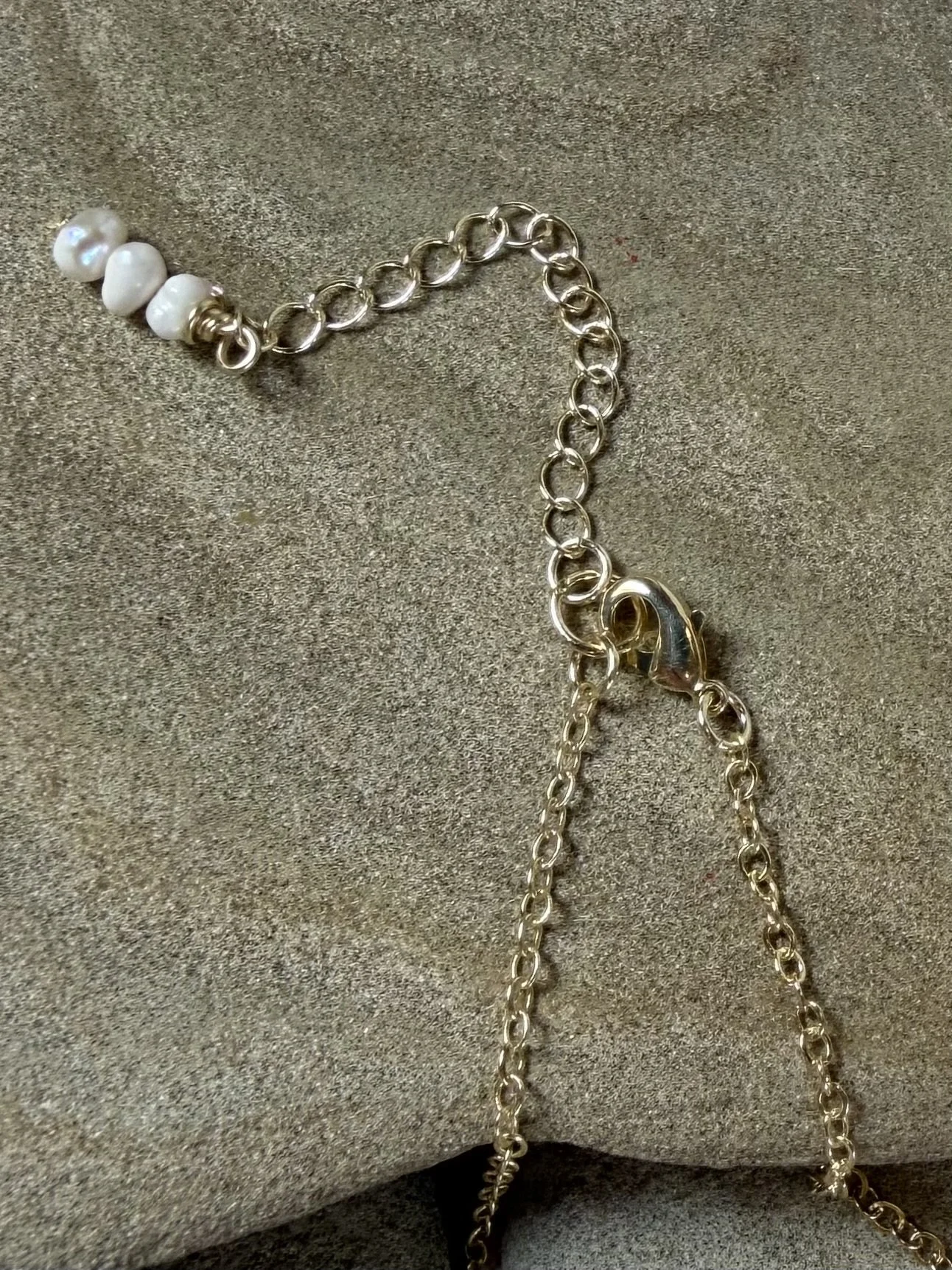 Close-up of the gold clasp and adjustable chain of a handmade gemstone necklace.