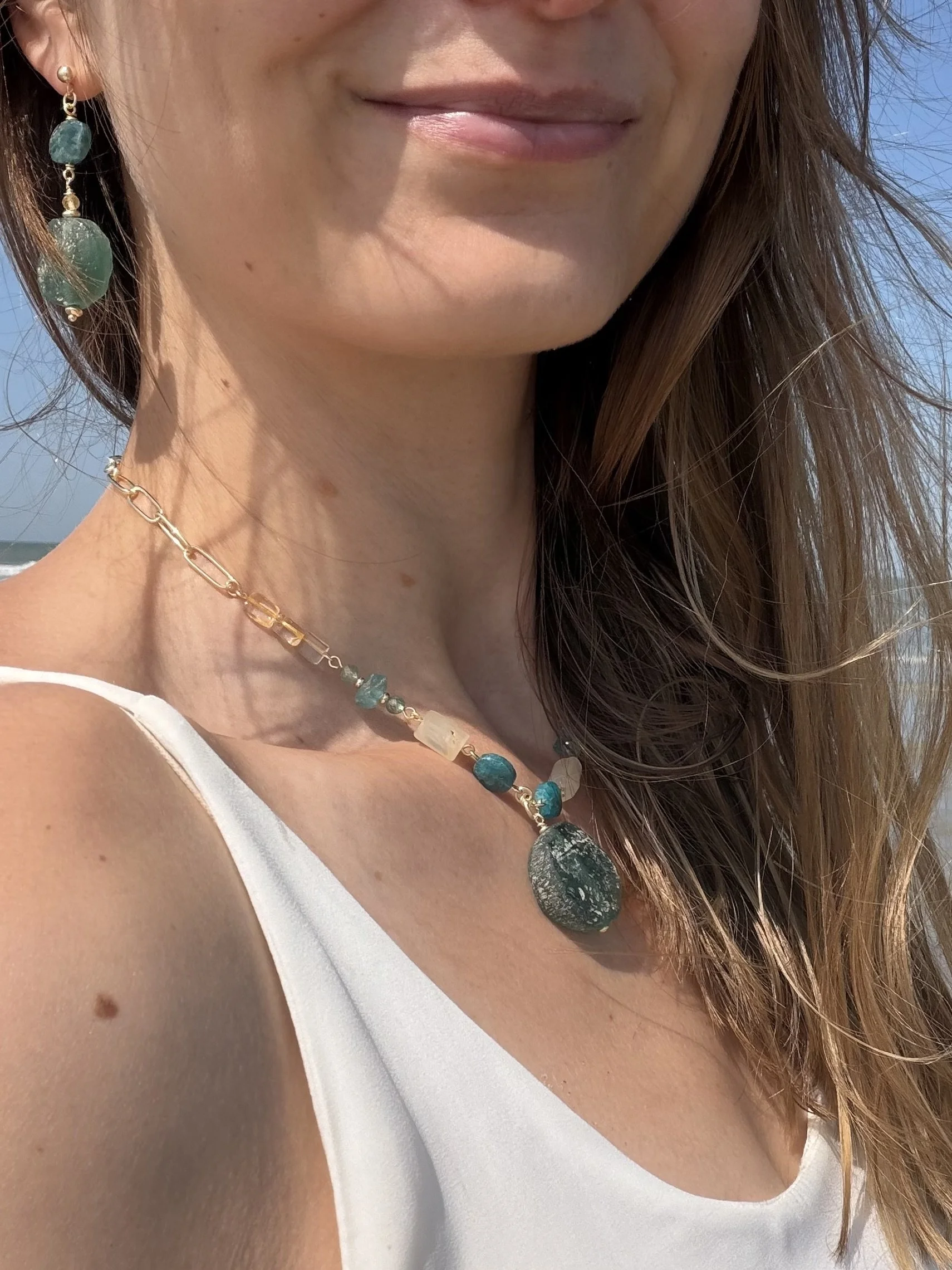 Green gemstone jewellery worn at the beach, showing a coordinating necklace and earring.