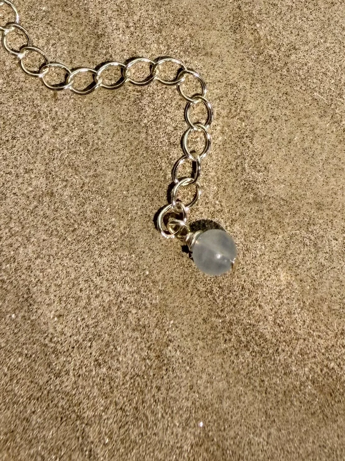 Close-up of the bracelet extender chain finished with a small gemstone charm.