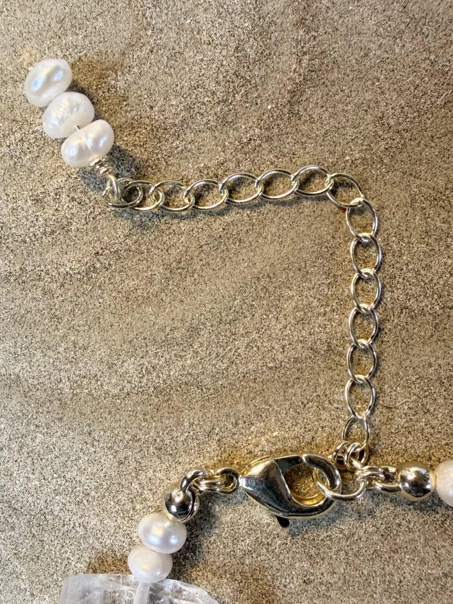 Close-up of the gold clasp and adjustable chain of a handmade gemstone bracelet.