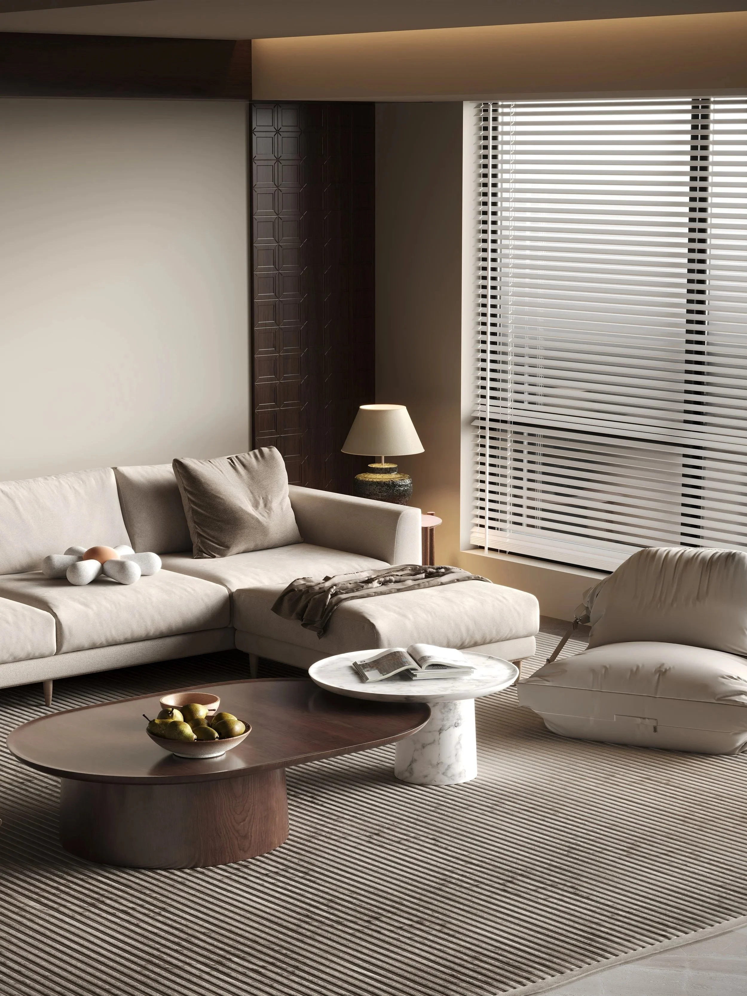 Modern living room with a white couch, a beige pillow, a patterned blanket, a round marble coffee table with a book, a dark wood oval coffee table with green pears, a white armchair, a table lamp, and large window with white blinds, beige walls, and a striped rug.
