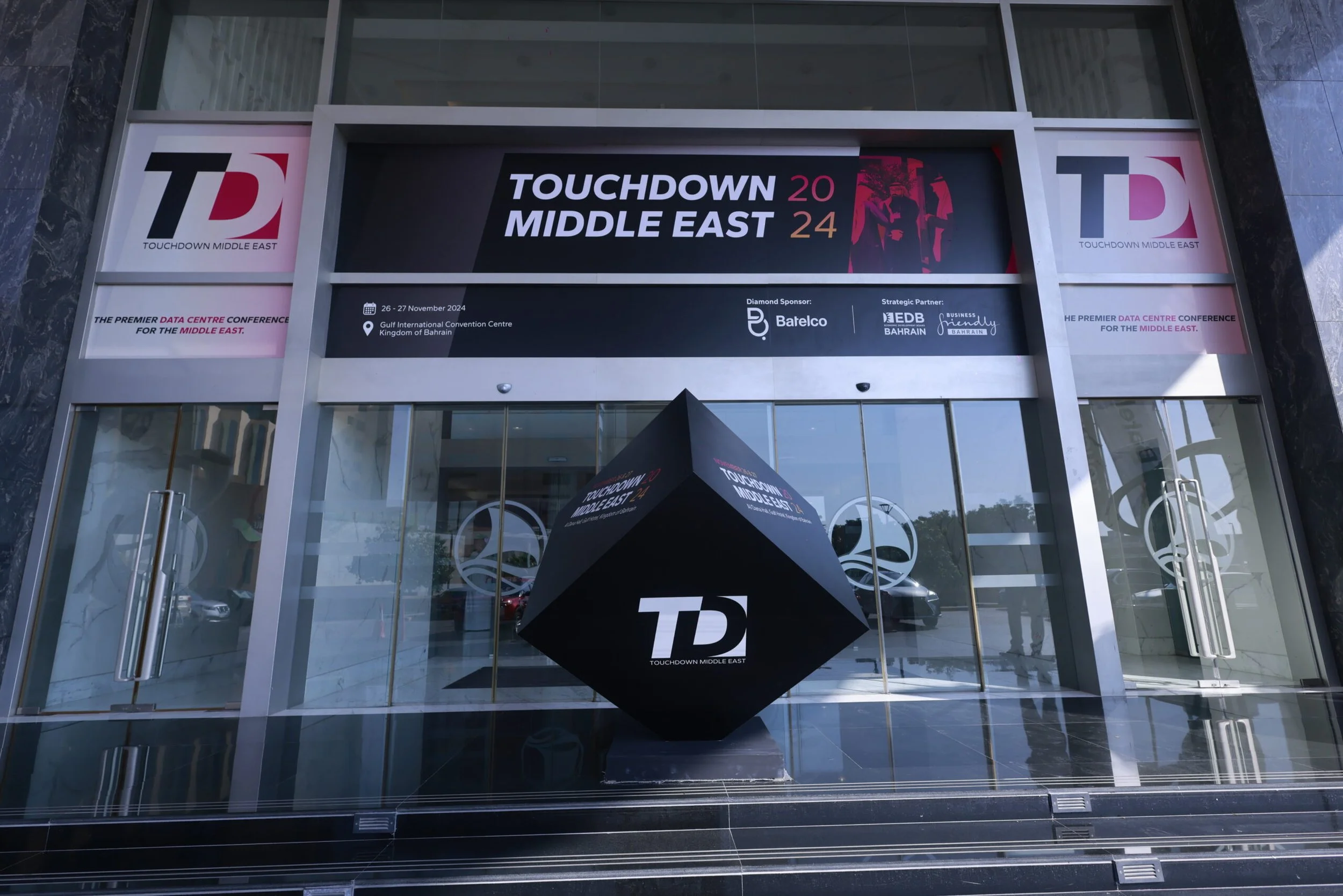 Entrance of the Touchdown Middle East conference venue with large digital banner displaying event details and logos, including date, location at Gulf International Convention Centre in Bahrain, and sponsors.