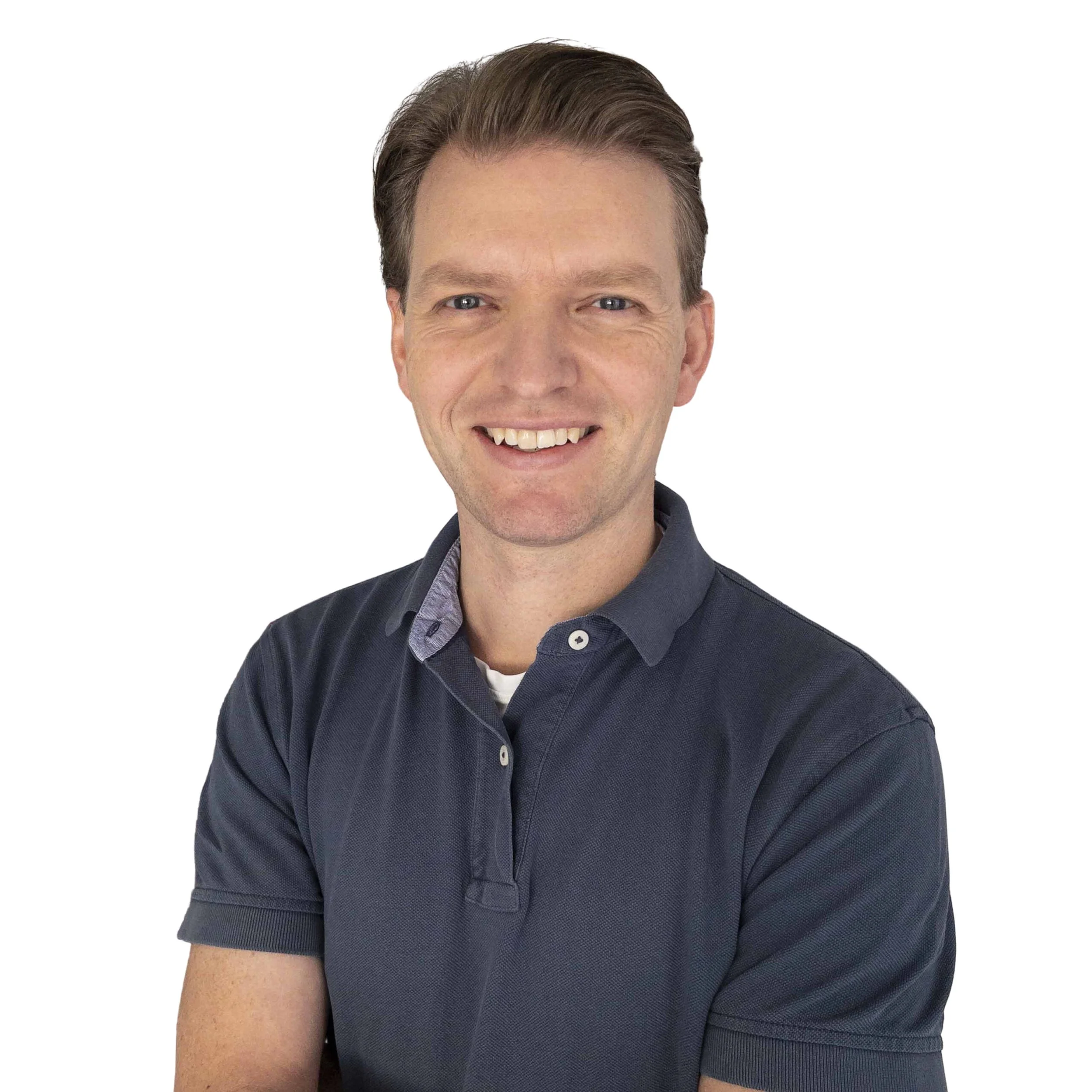 A man with short brown hair, blue eyes, and a big smile, wearing a dark blue collared shirt, against a plain white background.