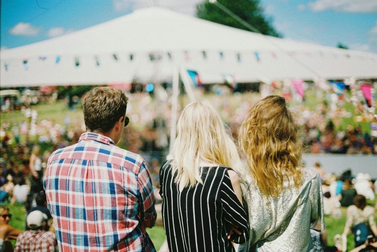 Three people sat facing a marquee at a wedding