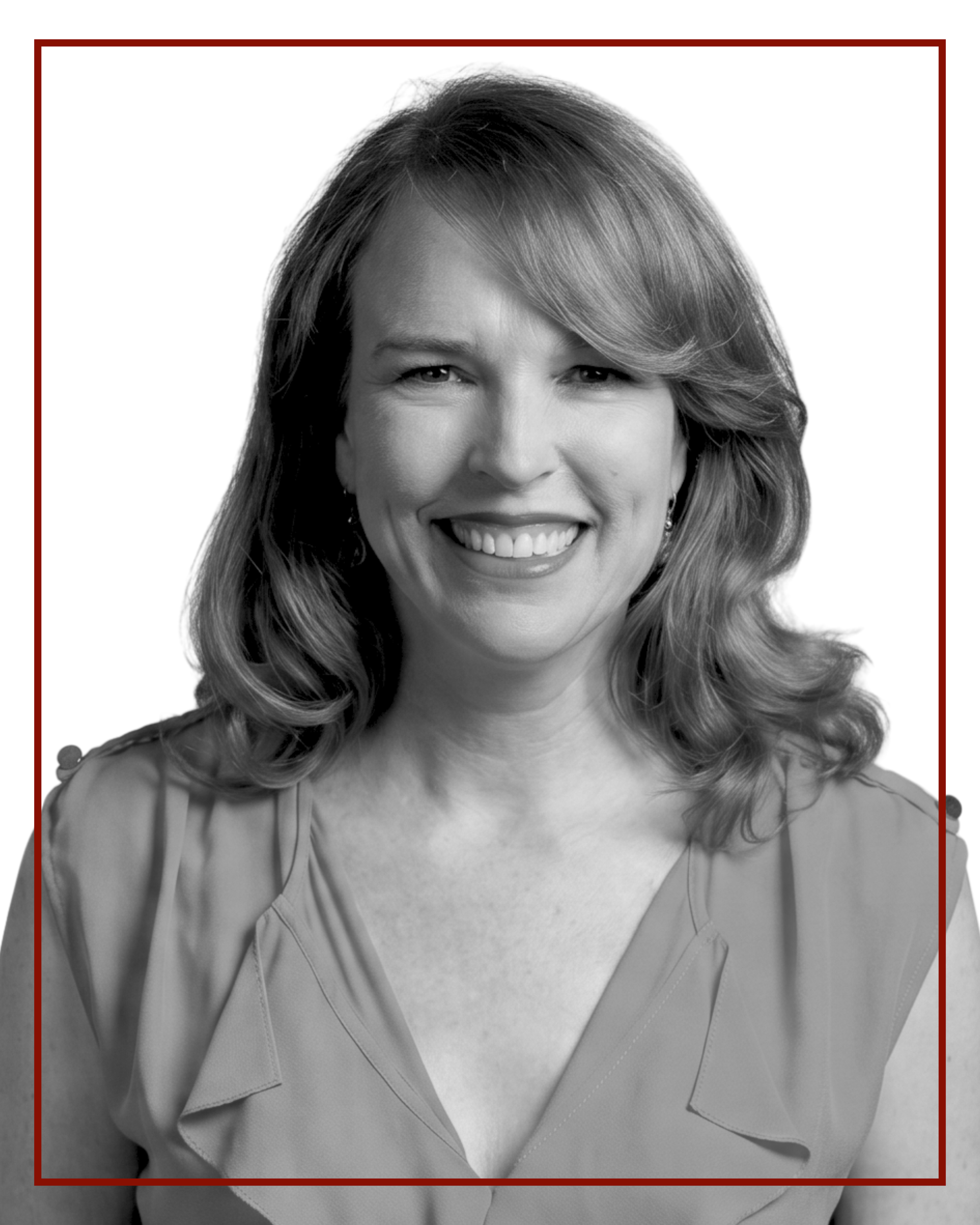 Black and white portrait of a smiling woman with medium-length wavy hair, wearing a blouse with ruffled sleeves.