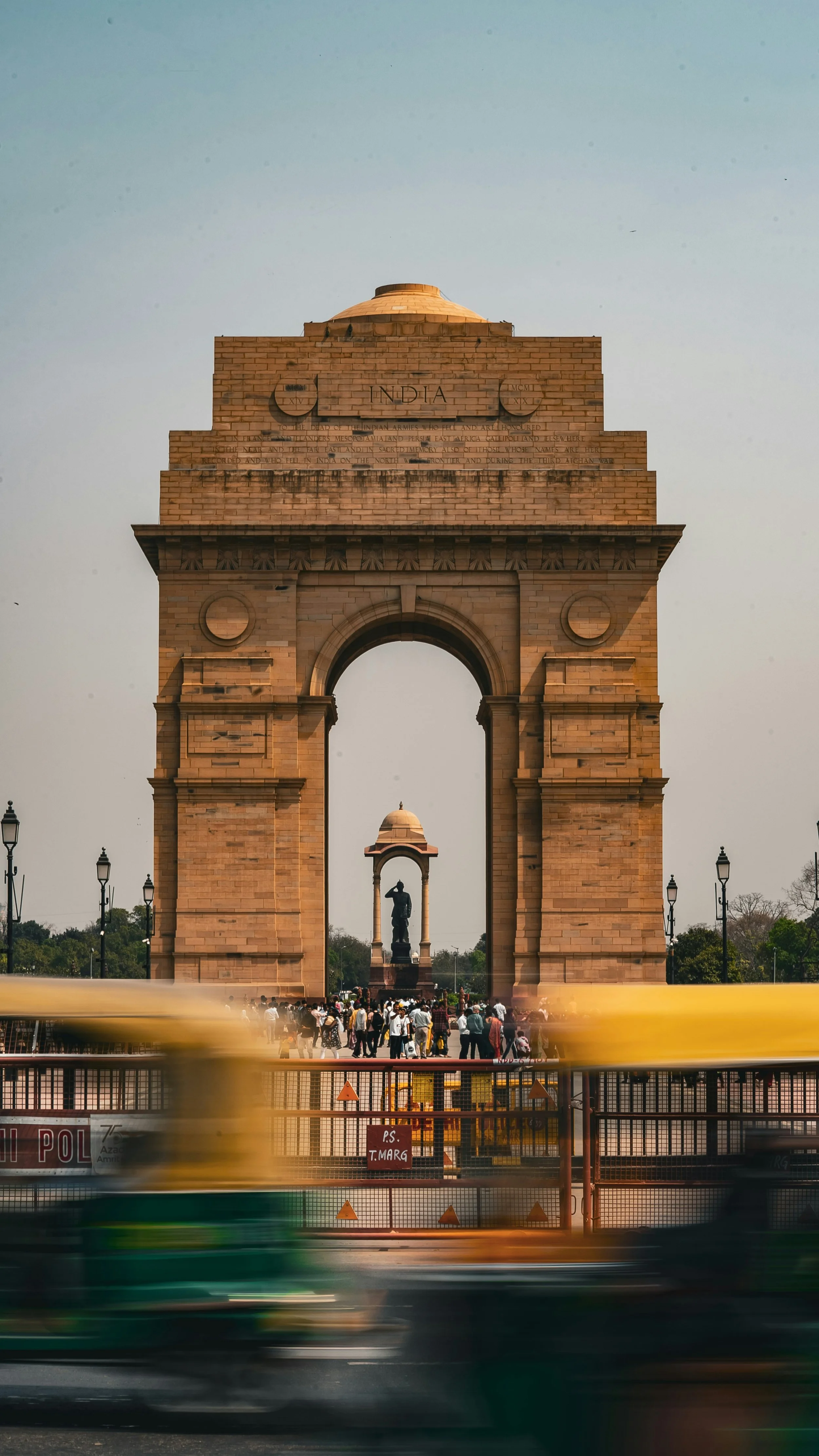 India Gate, a war memorial in Delhi, India, with people and a moving vehicle in front.