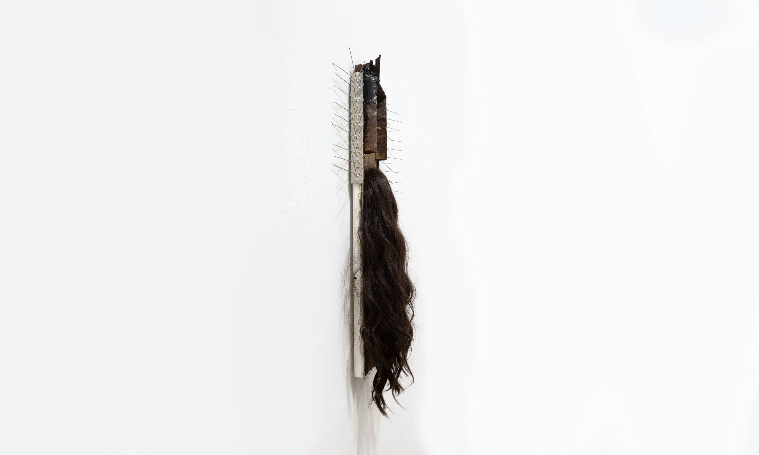 'Warning' (2025) | Found wood with three rusty nails, pigeon spikes, brown wig, metal frame, metal fragments, and black tar |
69 x 41 x 4cm