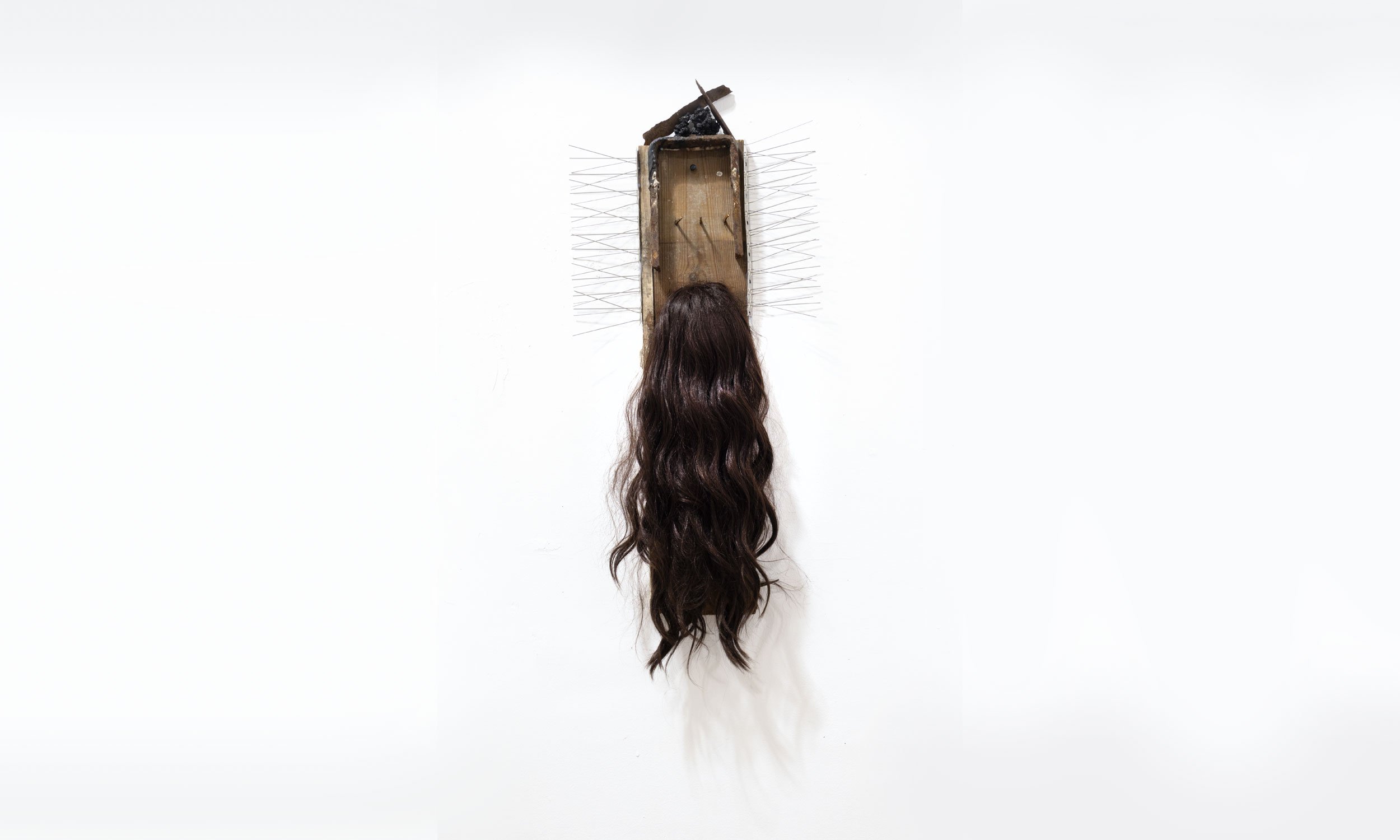 'Warning' (2025) | Found wood with three rusty nails, pigeon spikes, brown wig, metal frame, metal fragments, and black tar |
69 x 41 x 4cm