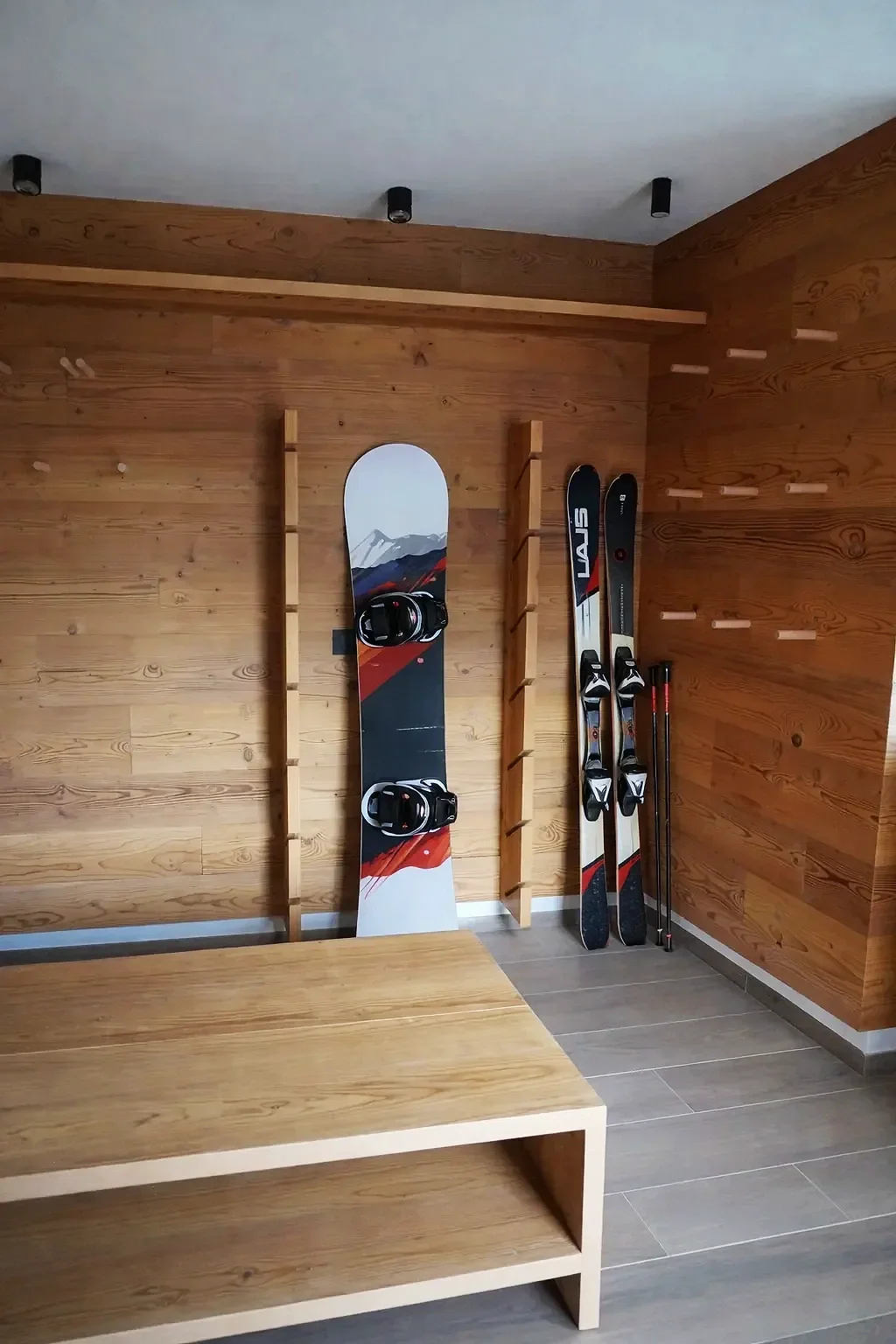 Attrezzature da sci e snowboard nell'armadietto di una cabina in legno.