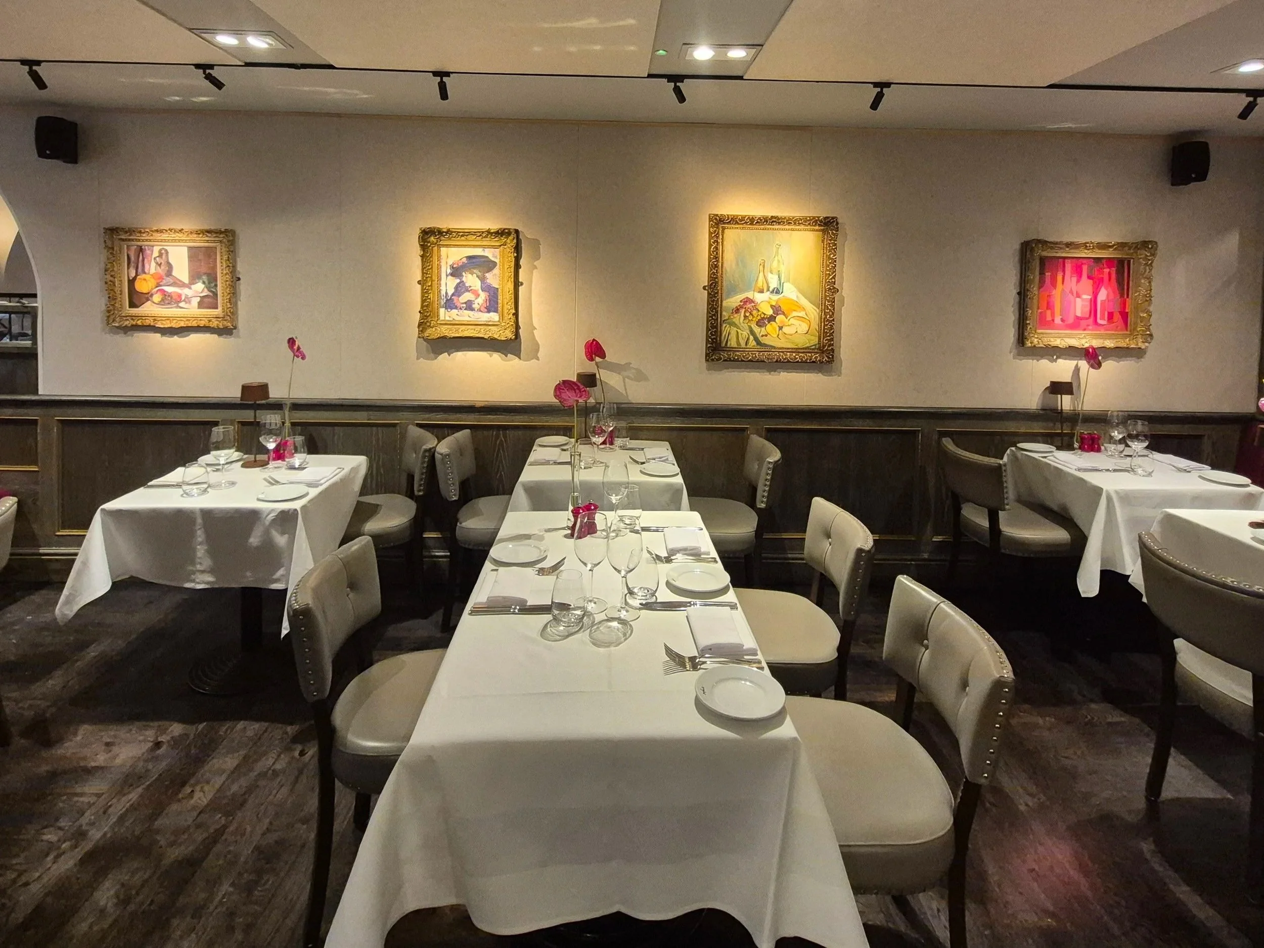 PET Acoustic Wall Panels in Elegant restaurant dining area with white tablecloths, wine glasses, and pink floral centerpieces, with framed artwork on the beige wall.