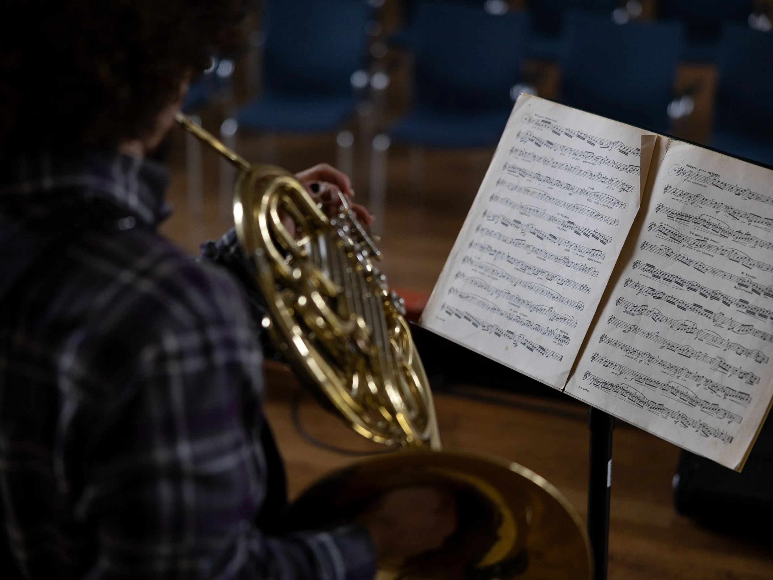 Person som spelar saxofon framför ett notblad i en repetitionslokal.