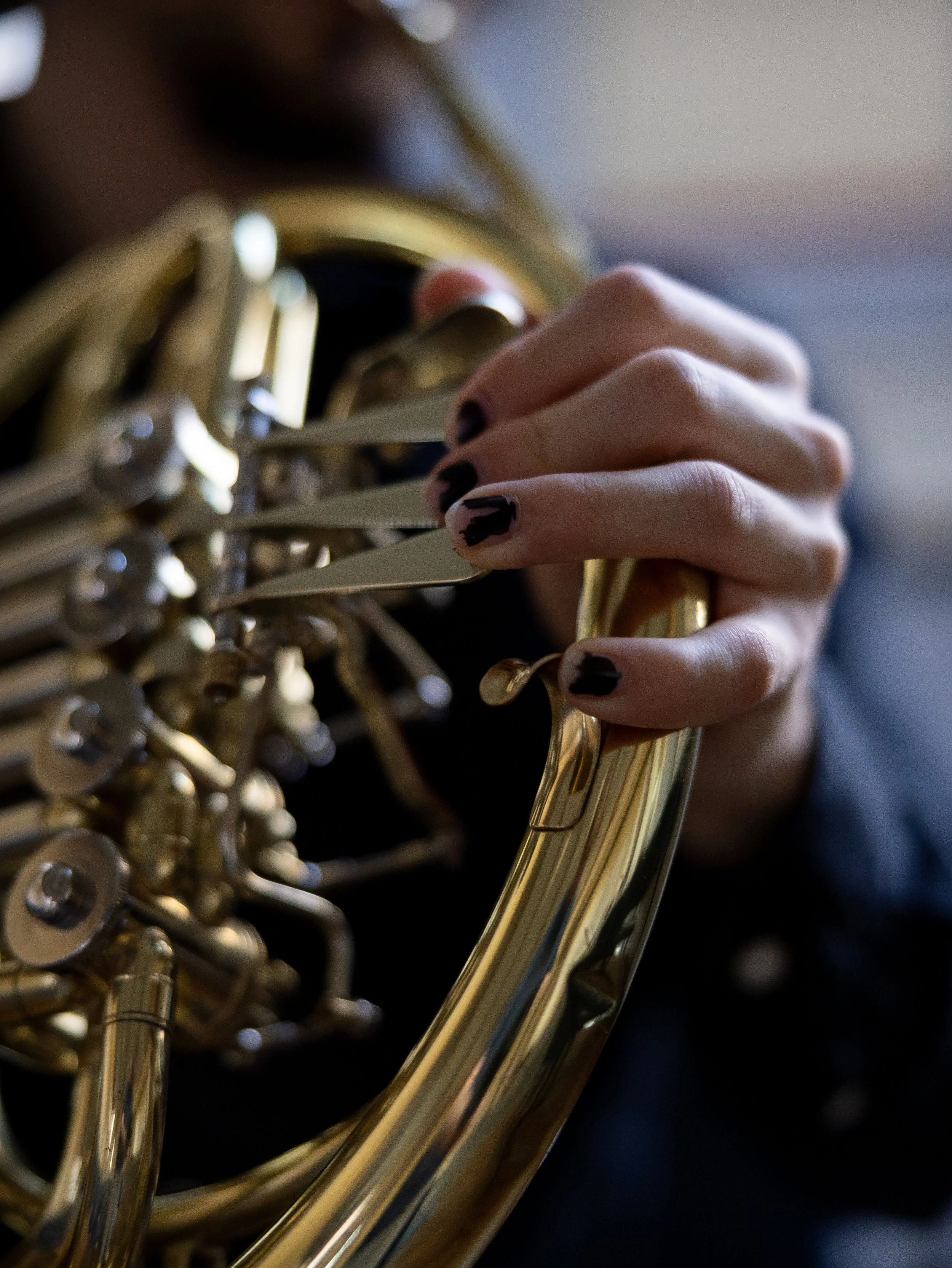 En närbild av en person som håller i en guldig saxofon, med fokus på instrumentets nycklar och det personliga fingret.