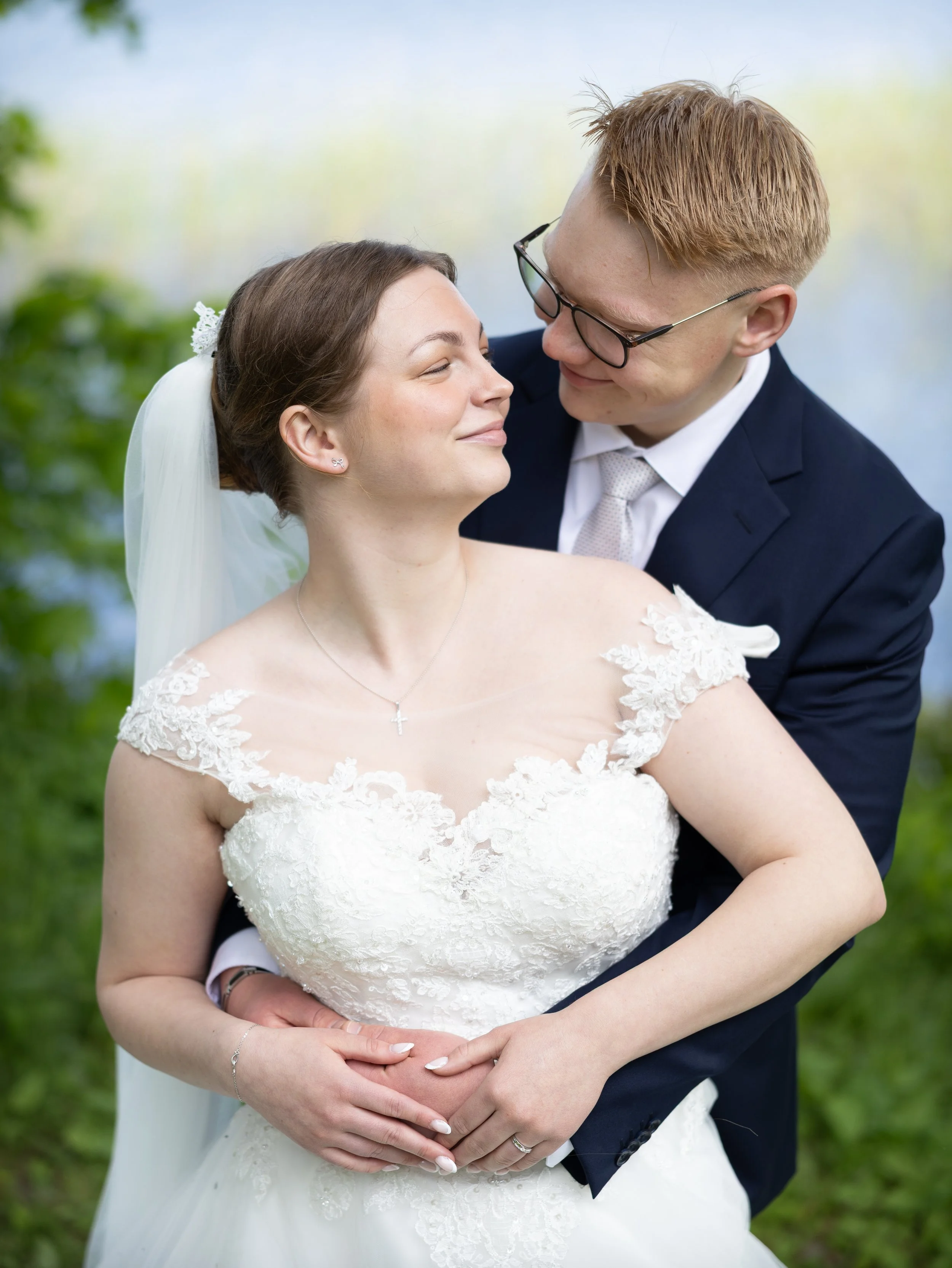 En nygift brud och brudgum gifter sig utomhus, omfamnar varandra och ler kärleksfullt.