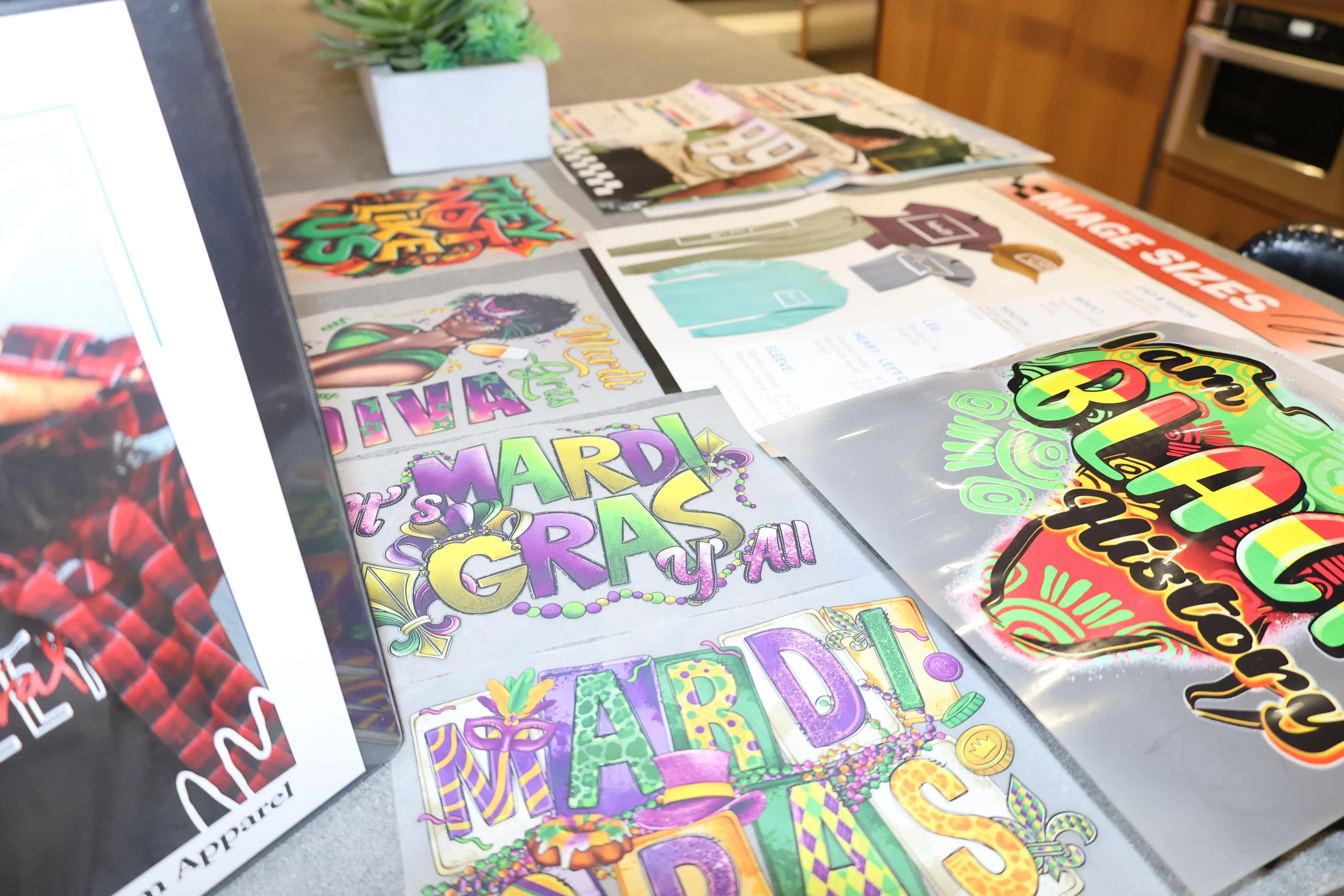 Colorful Mardi Gras and celebration-themed stickers and signs laid out on a table.