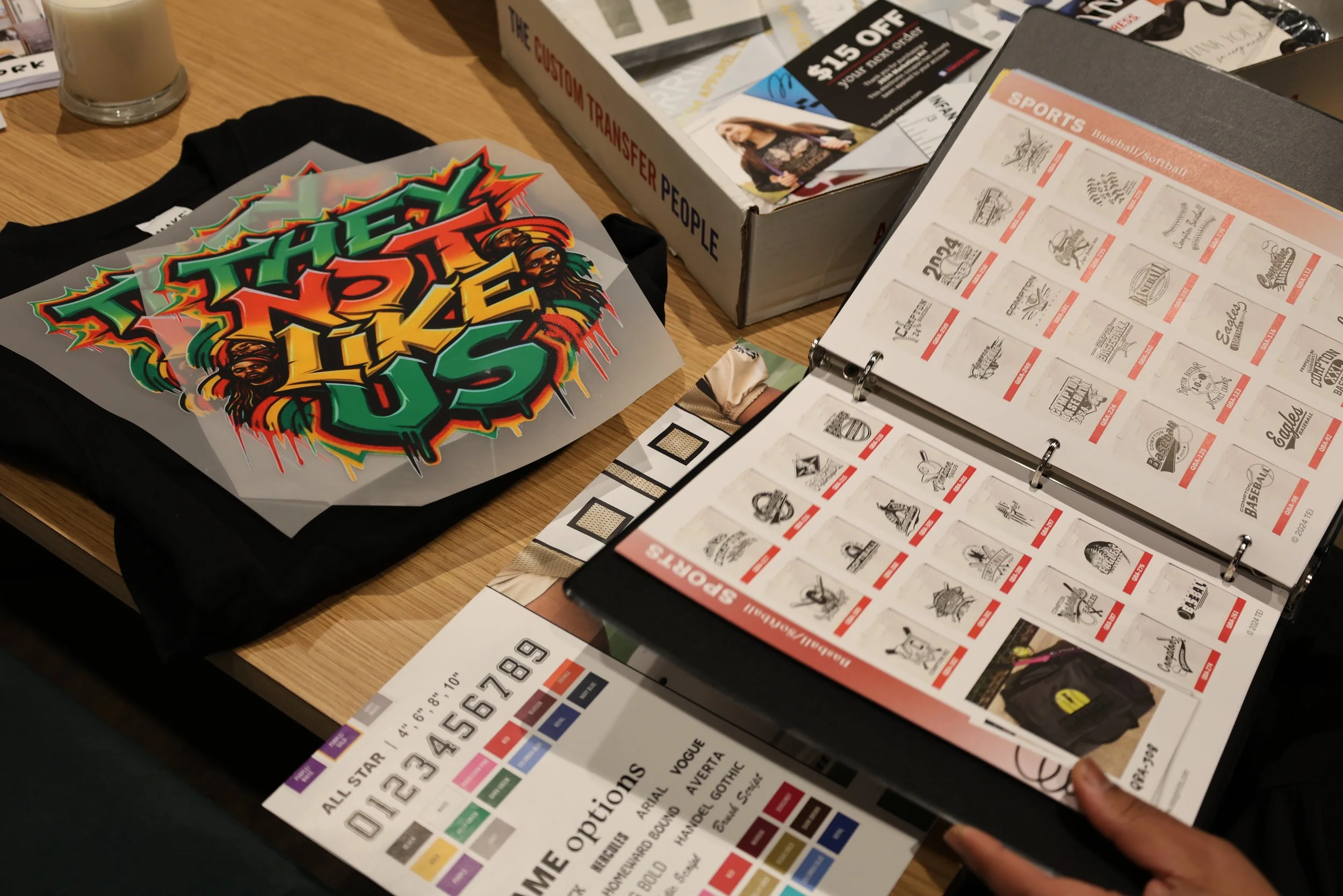 A table with various printed materials including stickers, brochures, and coupons, with a glass of coffee or latte in the background.