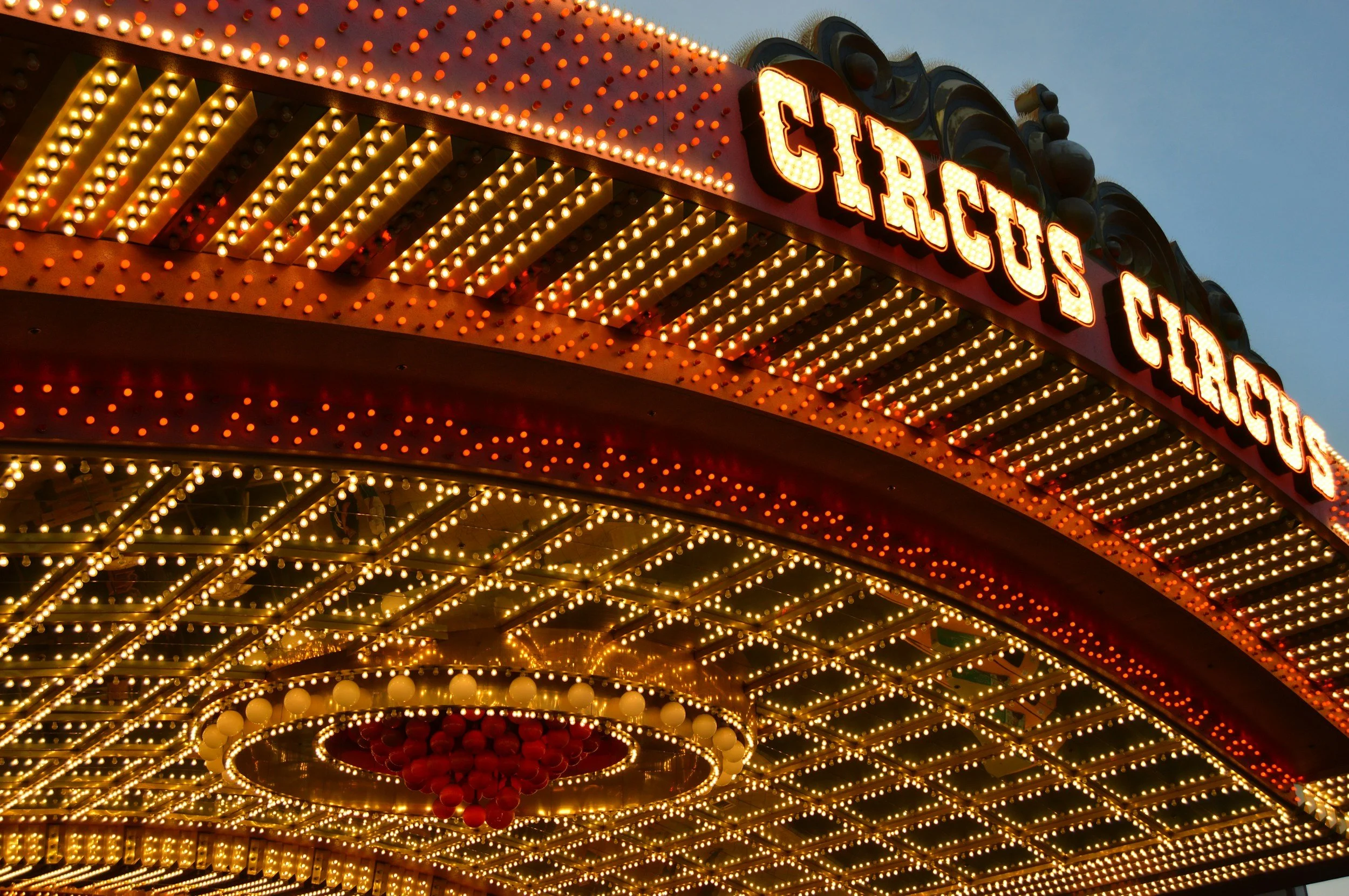 Lichterkugel- und Leuchtreklame auf einem Rummelkarussell bei Abenddämmerung, lettering 'Circus' auf neonbezogener Leuchttafel