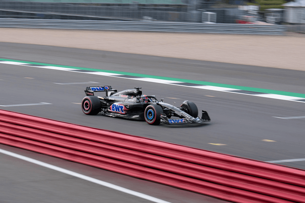 A black Formula 1 race car with BWT sponsorship accelerating on a race track.