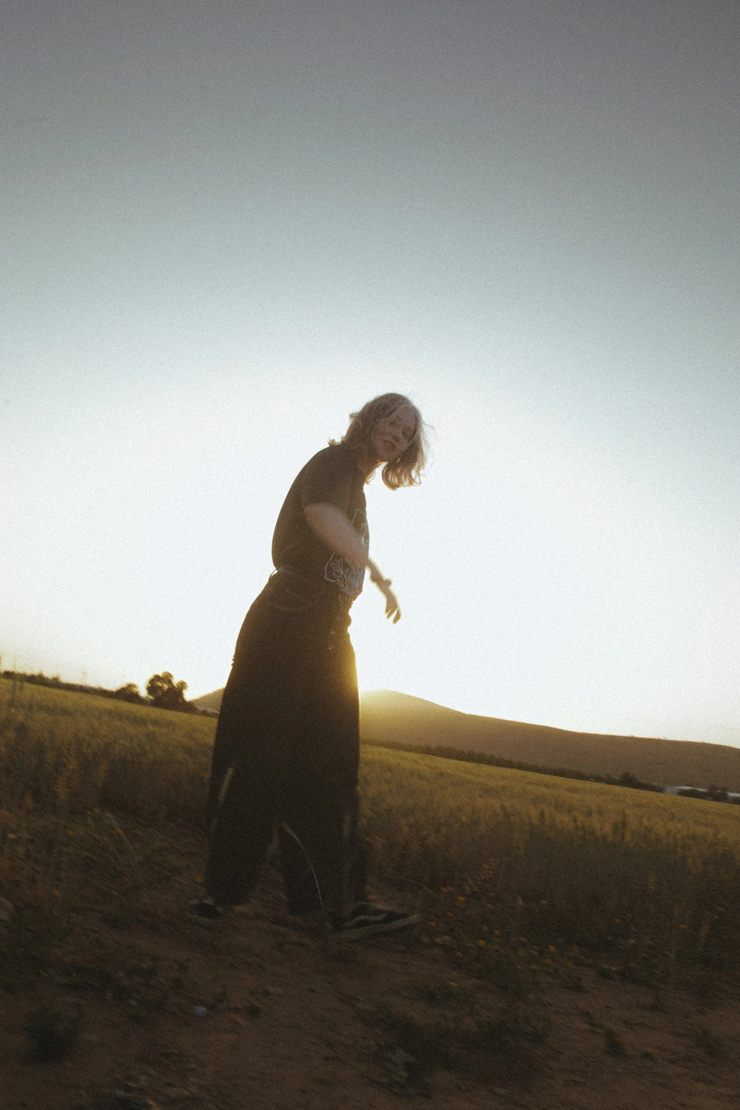 Une femme dans un champ lors du coucher du soleil.