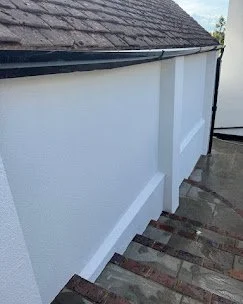 Close-up of a white exterior wall with brick steps leading down.