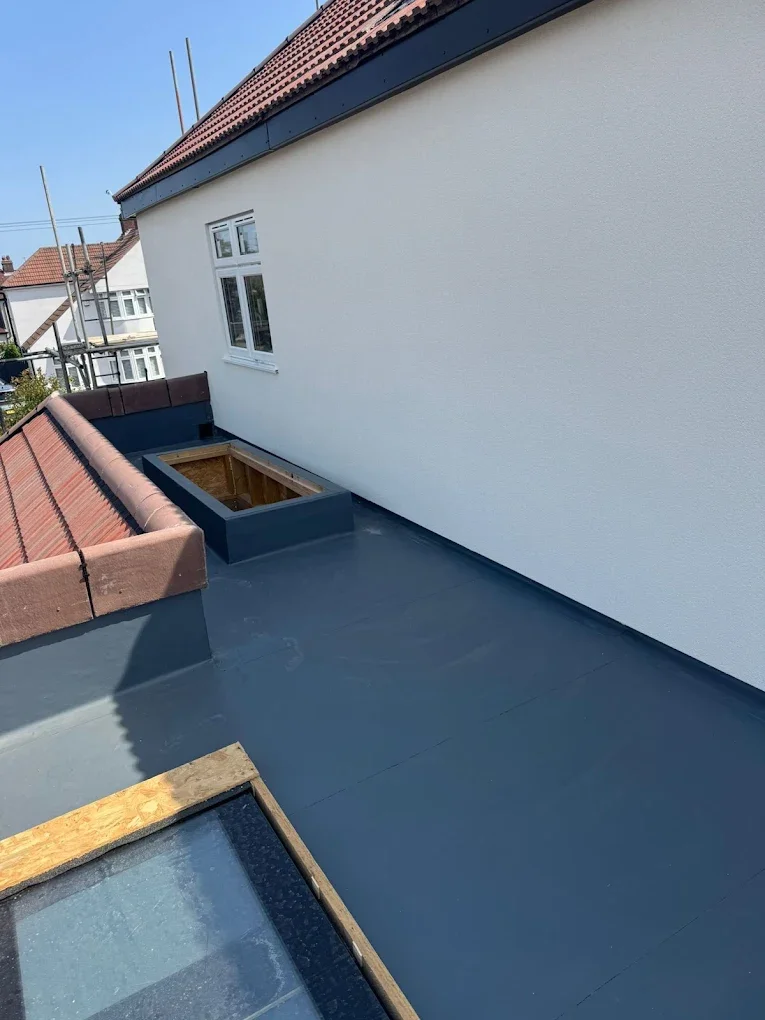 A rooftop with new roofing material, a white wall with a window, a section with a red tile roof, and a construction opening with wooden framing.