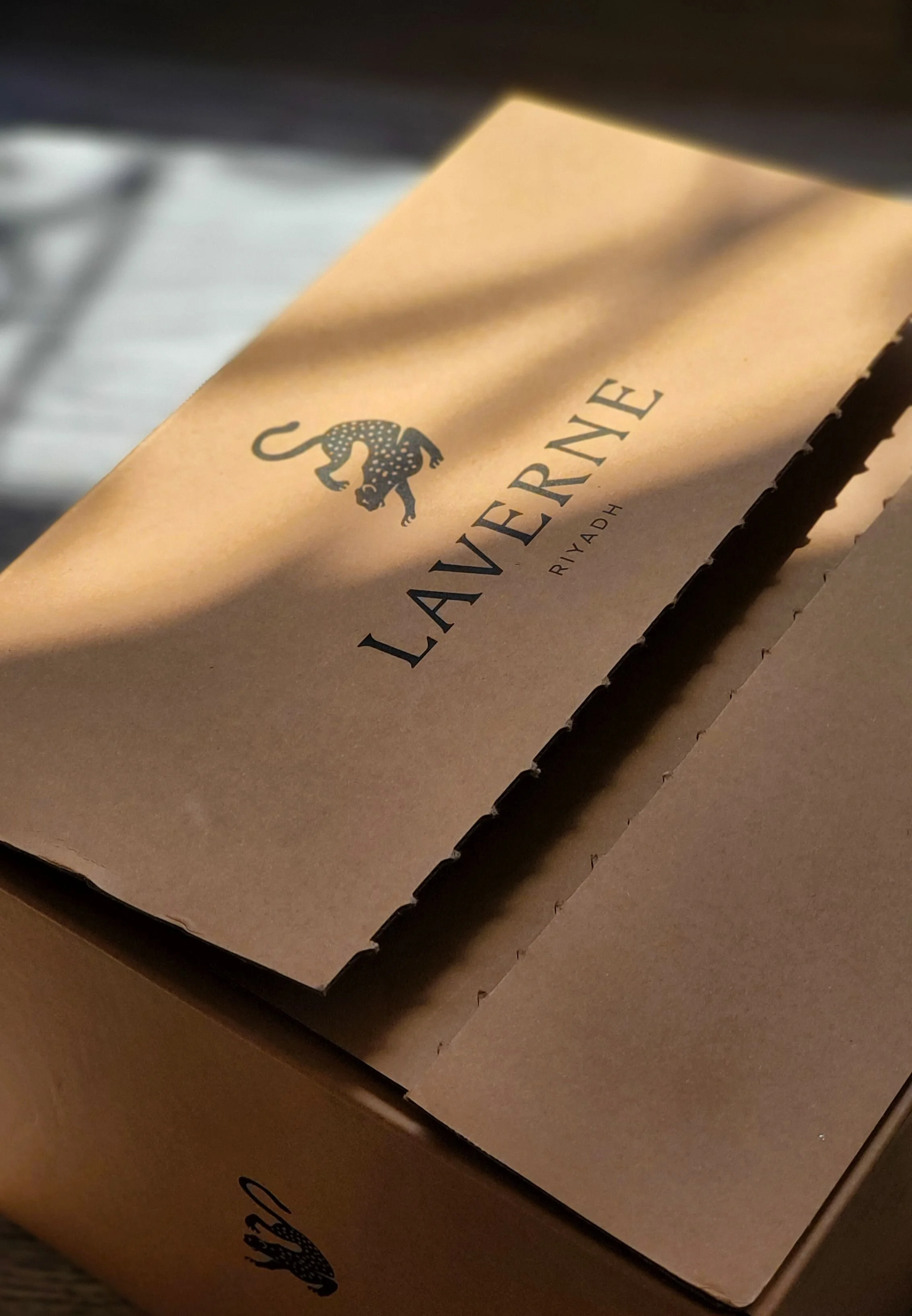Close-up of a brown cardboard box with the Lavera logo, a black silhouette of a gecko, printed on it.