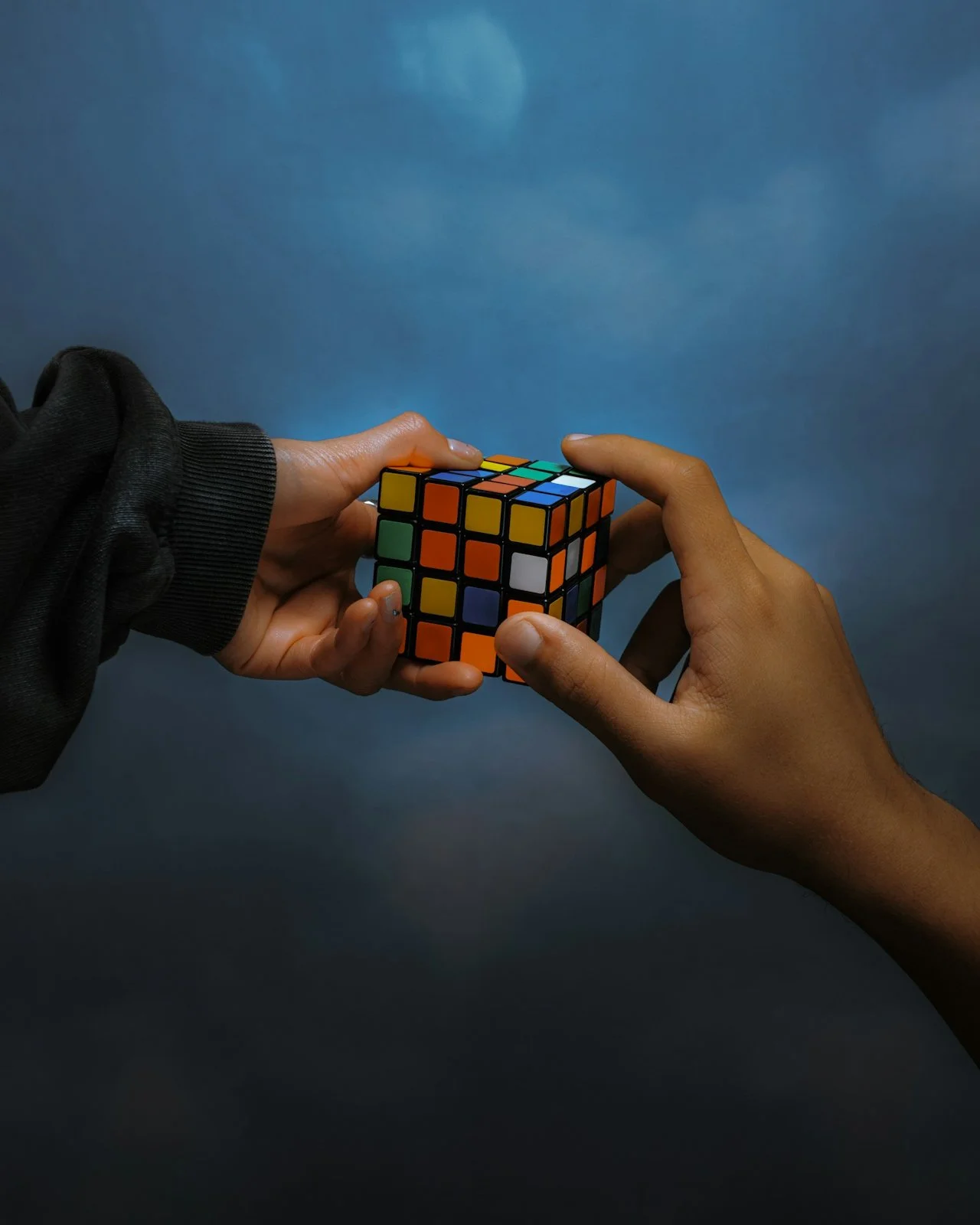 Deux mains manipulant un Rubik's Cube contre un fond bleu.