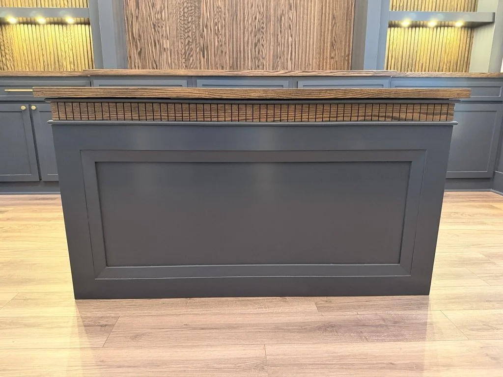 Blue kitchen island with a wooden top and a fenced side, surrounded by blue cabinetry.